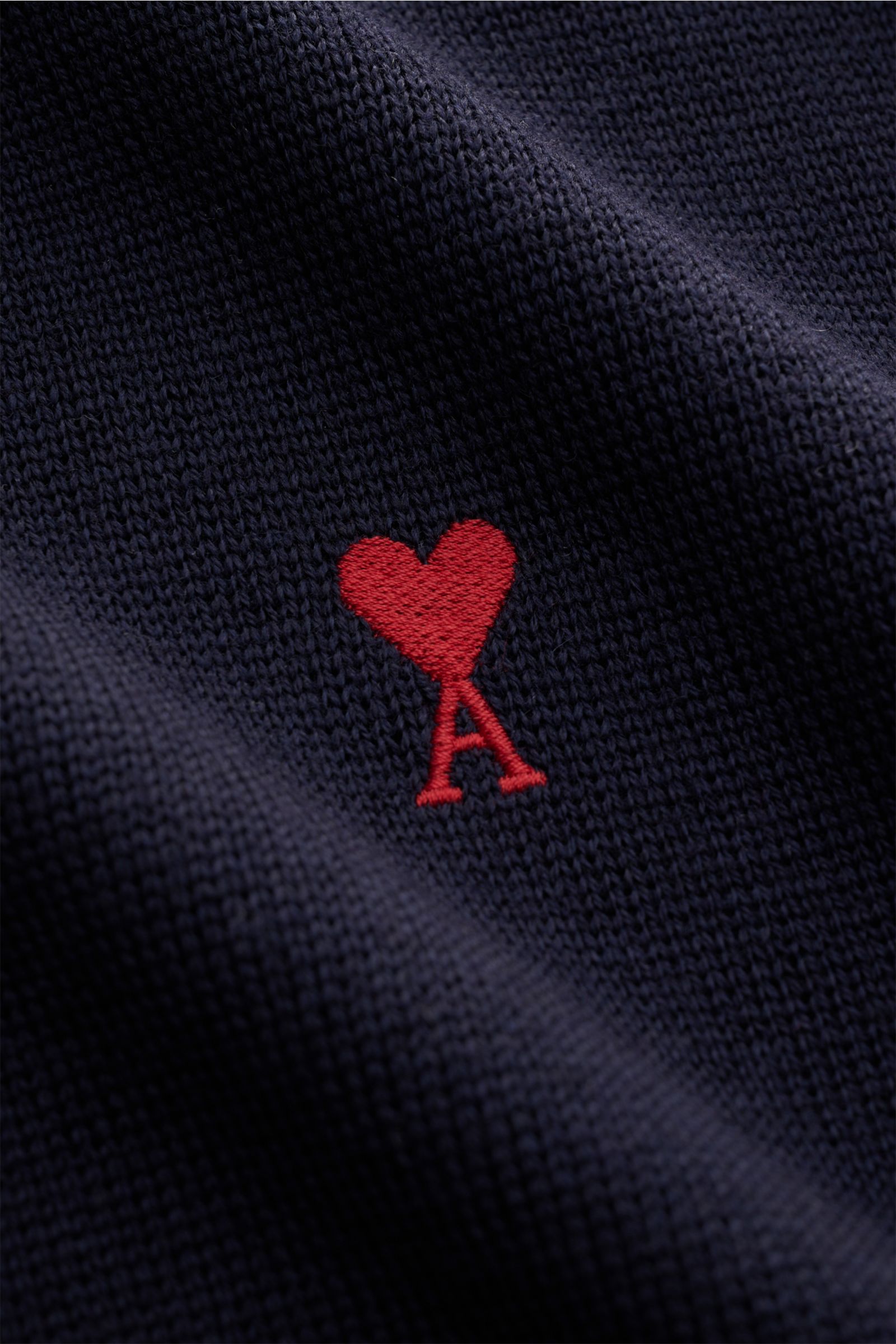 Nahaufnahme des Ami Paris Merino Rundhalspullover navy mit feinem Strickbild und rotem Logo-Stitching auf der Brust aus reiner Merinowolle.