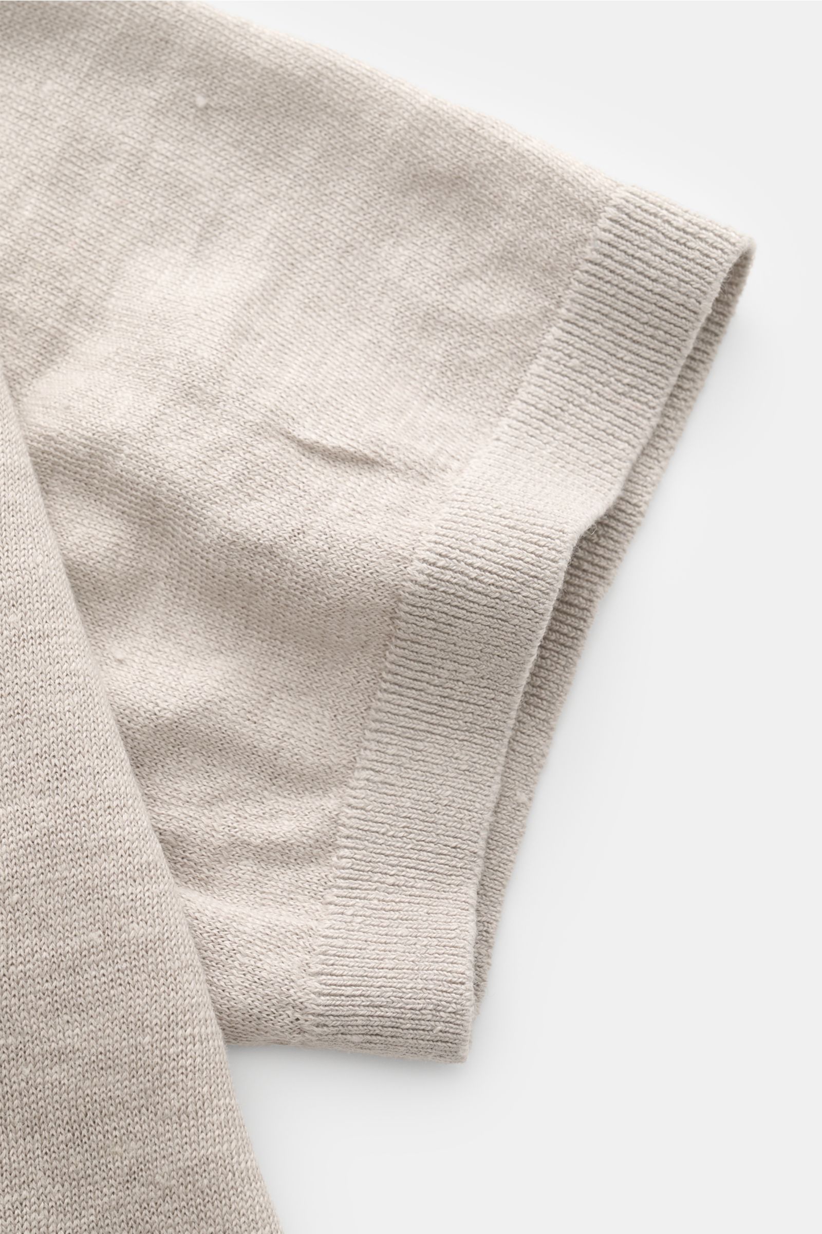 Nahaufnahme des Ärmels vom C.P. Company Kurzarmpullover grau aus feinem, weichem Leinenstrick mit elastischem Rippbündchen, seitliche Perspektive.