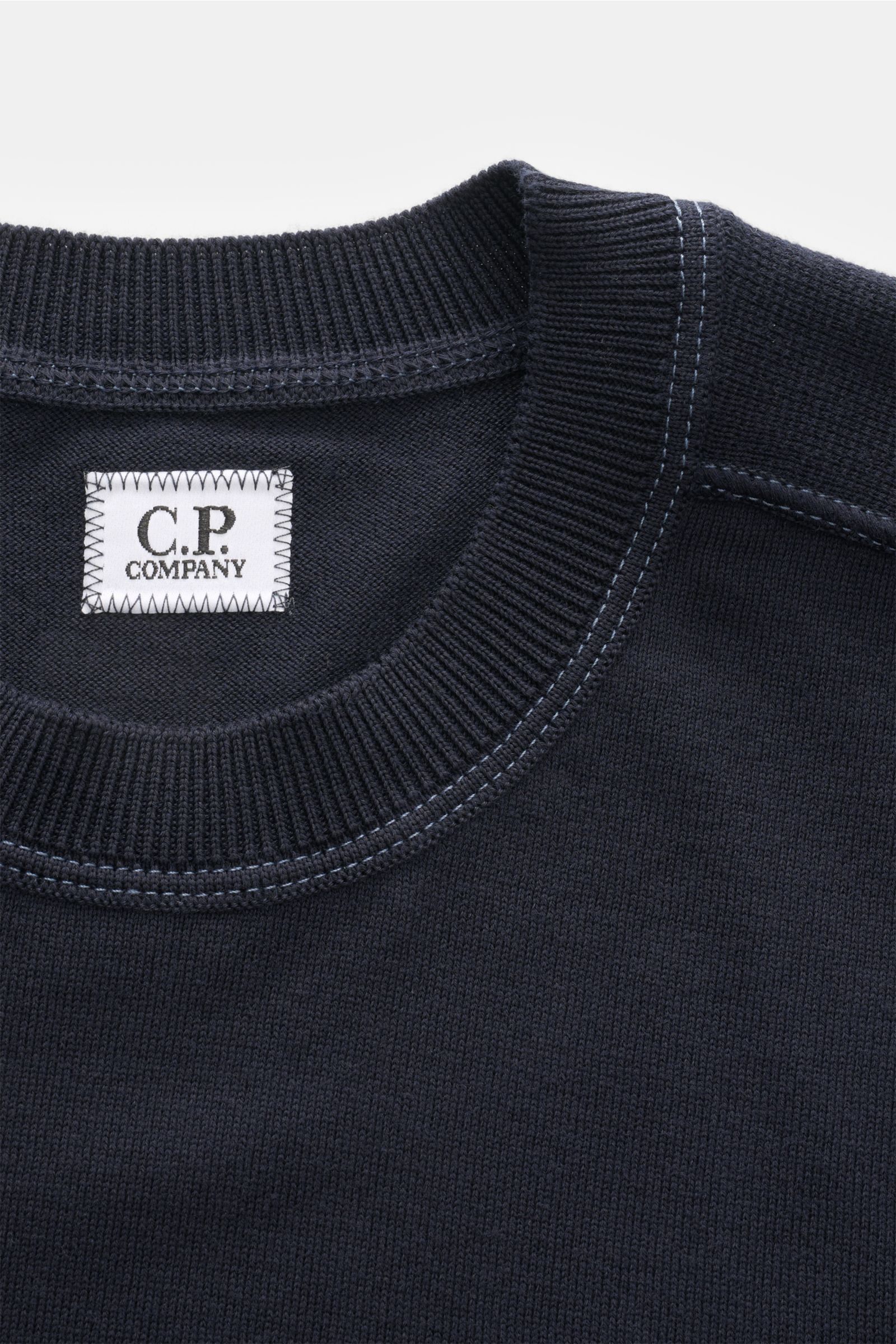 Nahaufnahme des C.P. Company Rundhalspullover navy von oben, zeigt feine Strickstruktur, Rundhalsausschnitt und kontrastierende Nähte.