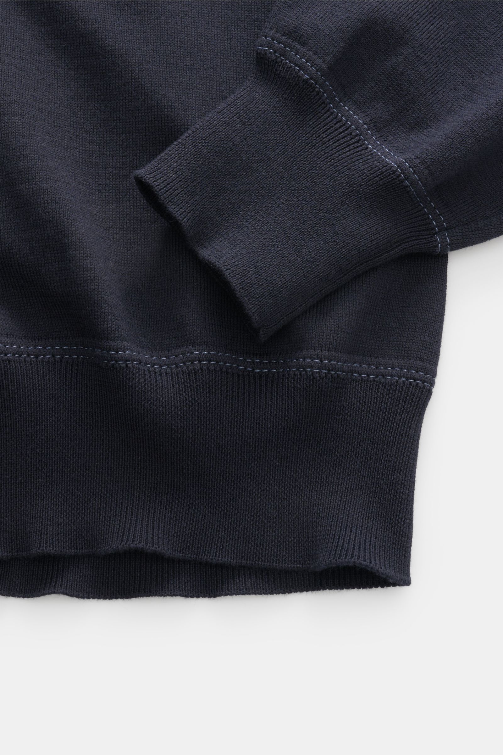 Nahaufnahme des unteren Bereichs und Ärmelbündchens des C.P. Company Rundhalspullover navy aus gestrickter Baumwolle, Sweatshirt-Stil, mit feinem Strickbild und Kontrastnähten.