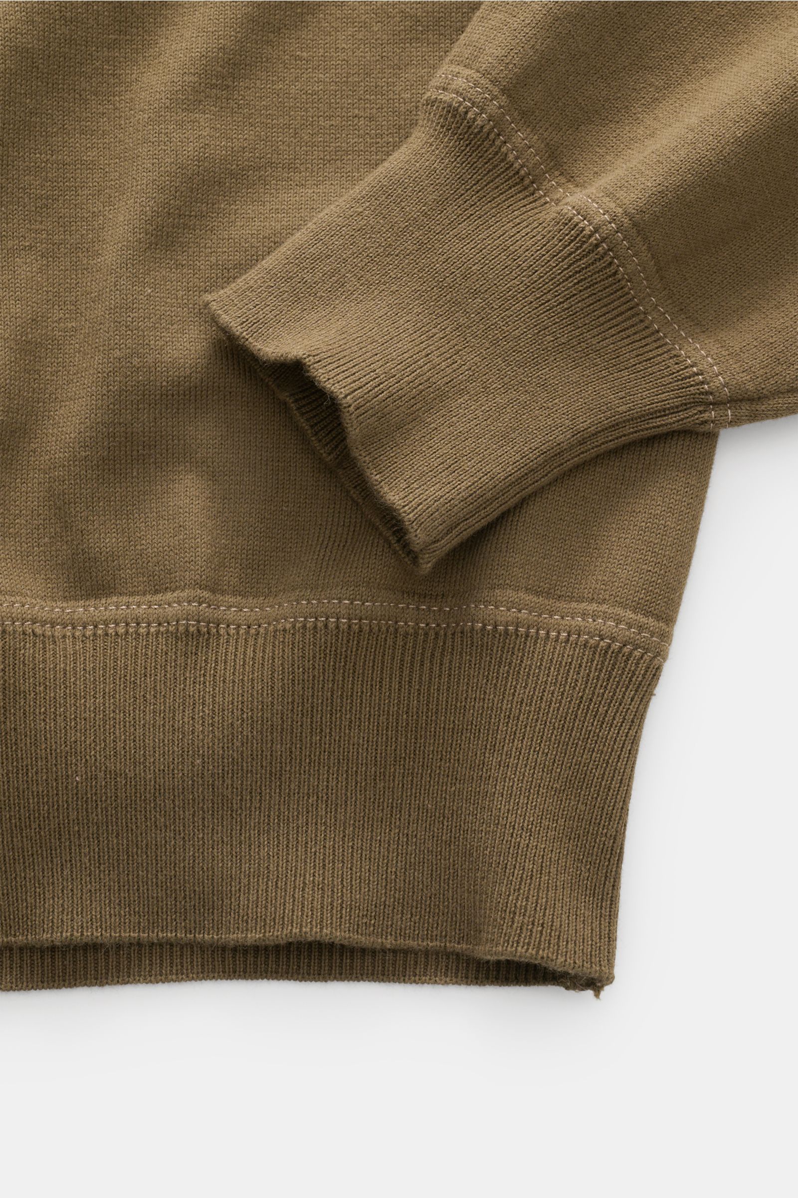Nahaufnahme des C.P. Company Rundhalspullovers oliv, Fokus auf Ärmel und Saum mit feinem Strick und Sweatshirt-ähnlichen Nähten.