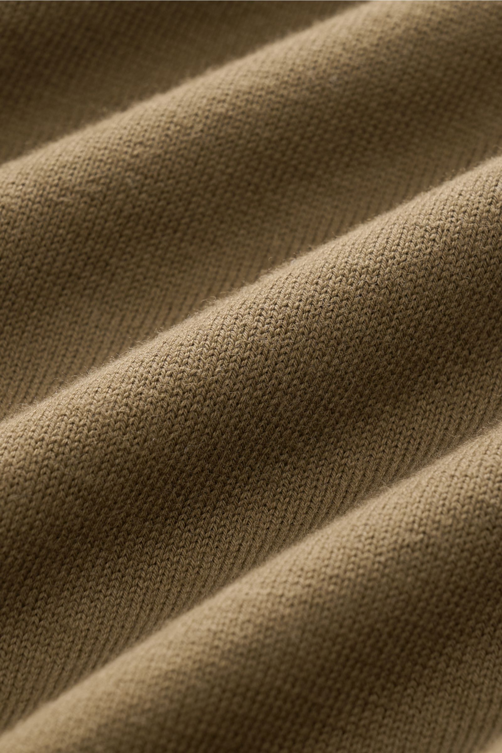 Nahaufnahme des feinen Strickbilds eines olivfarbenen C.P. Company Rundhalspullover aus weicher Baumwolle, Detail von oben.