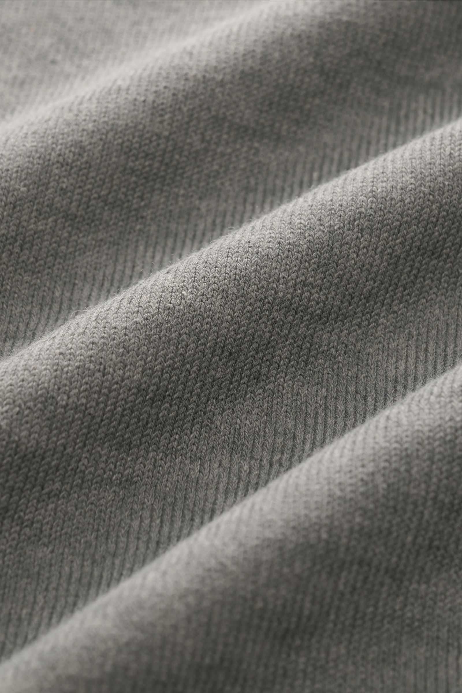 Nahaufnahme des feinen Strickbilds des grauen C.P. Company Rundhalspullover mit weichem Griff und markantem Garment-Dyed-Design.