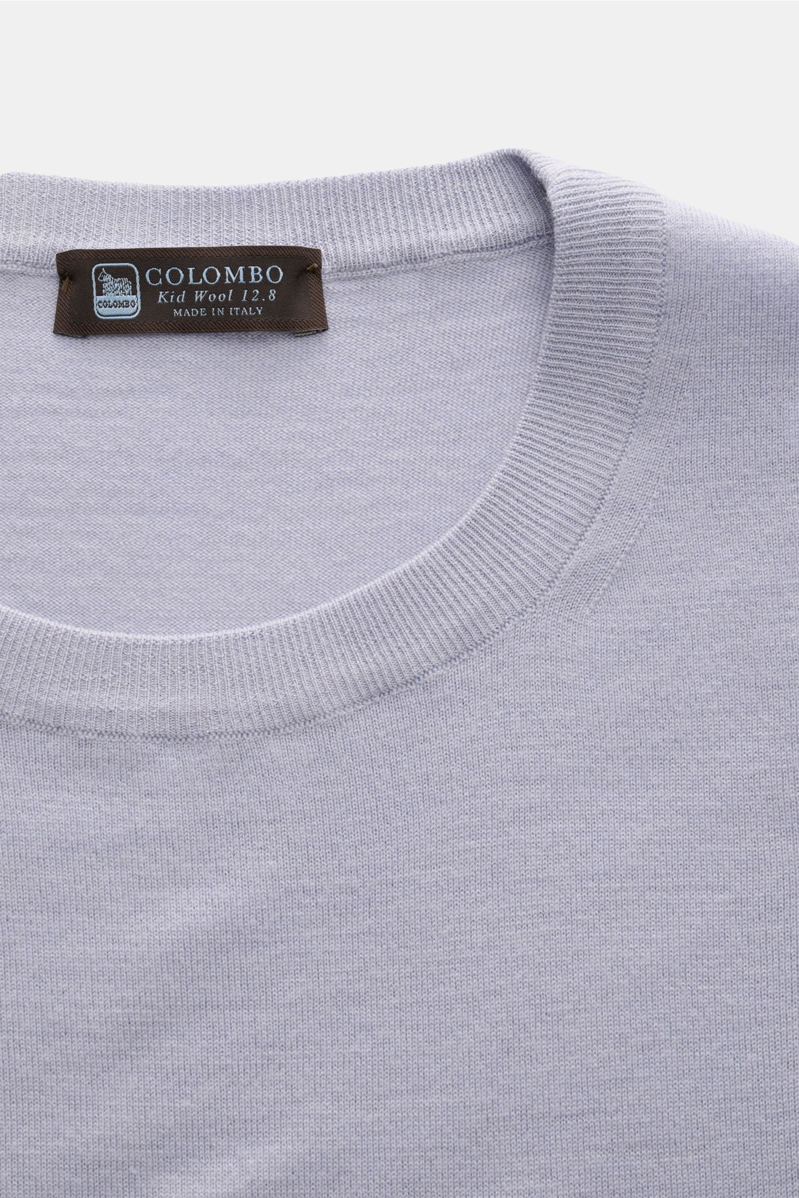 Close-up top view of Colombo Kurzarmpullover rauchblau showcasing the round neckline and soft ribbed cuffs in subtle luxury kid wool.

Subtiler Luxus: Gefertigt aus exklusiver 'Kid Wool', überzeugt der Kurzarmpullover mit außergewöhnlicher Feinheit und