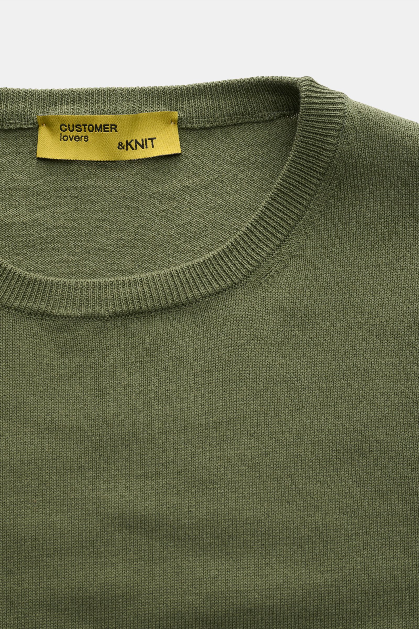 B.F. Knitwear Rundhalspullover oliv in Slim Fit, aus reiner Baumwolle mit feinem Strickbild, Rundhalsausschnitt und Rippbündchen, Nahaufnahme von oben.