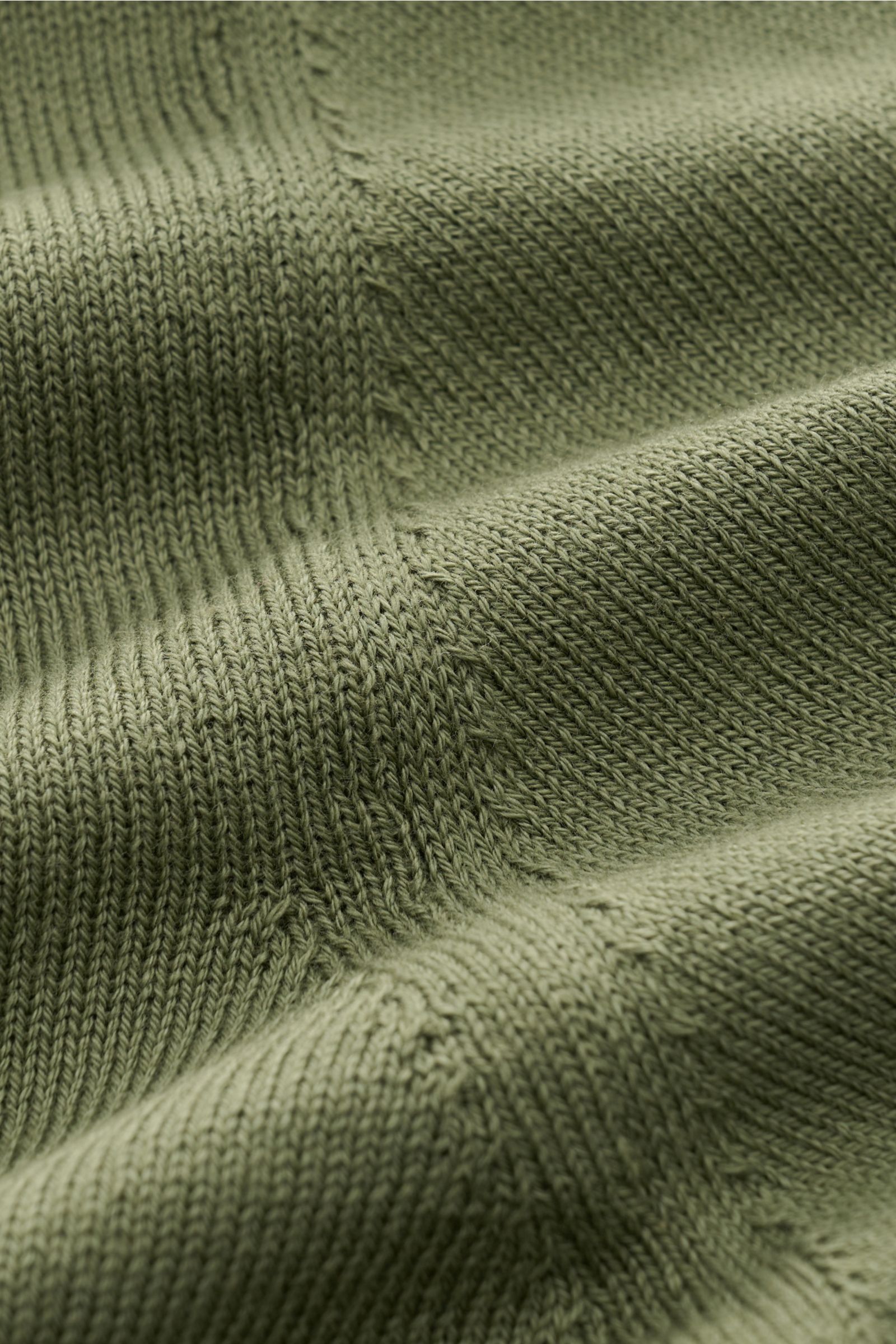 Nahaufnahme des feinen Strickbilds und weichen Griffs des olivfarbenen B.F. Knitwear Rundhalspullovers aus reiner Baumwolle.