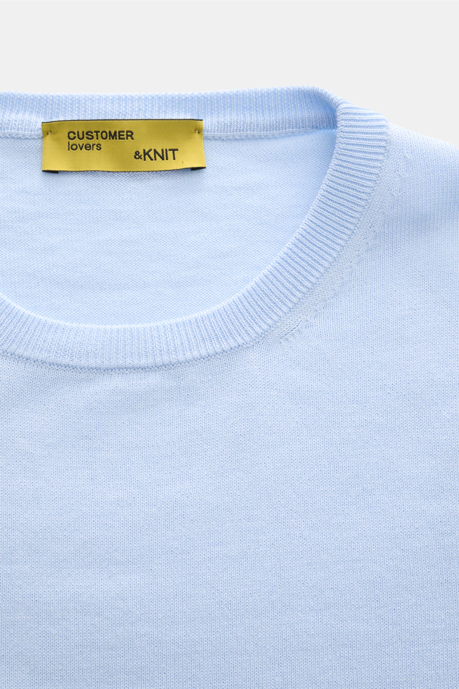 B.F. Knitwear Crew neck jumper light blue shown from a close-up top-down perspective, highlighting the fine knit, soft pure cotton fabric, slim fit, crew neck, and comfortable ribbed bands. A versatile essential for spring with a clean, timeless aesthetic