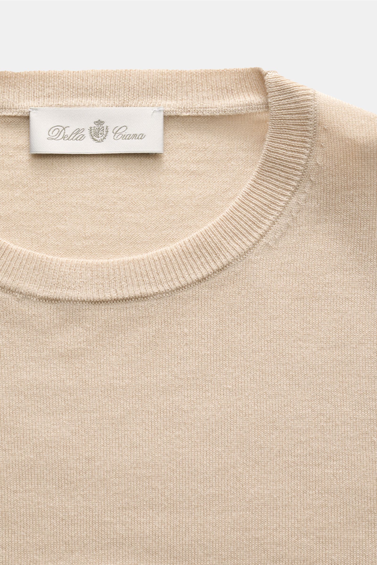 Close-up front view of the beige Della Ciana Feinstrick-Rundhalspullover 'Girocollo' showing its fine knit texture, round neckline, ribbed collar, and label, made from a soft silk and cashmere blend with a slim fit and lightweight quality. 