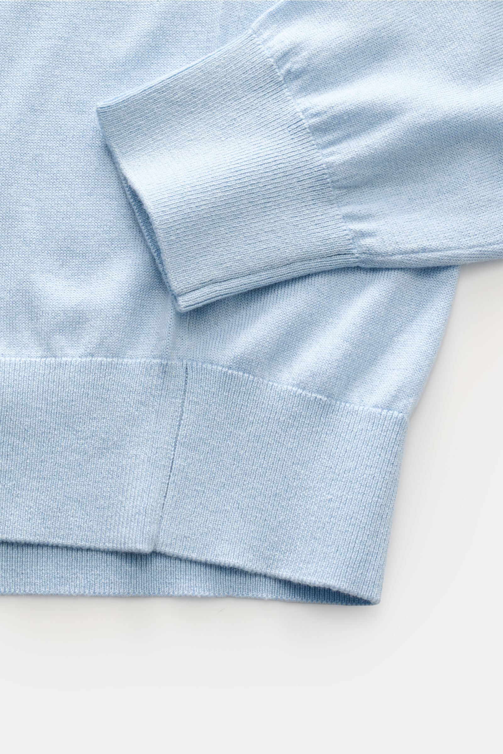 Close-up of the sleeve and hem of the Della Ciana Feinstrick-Rundhalspullover 'Girocollo' pastellblau, showing its soft, fine knit silk-cashmere blend, slim fit, round neckline, and comfortable ribbed cuffs from a top-down perspective. 