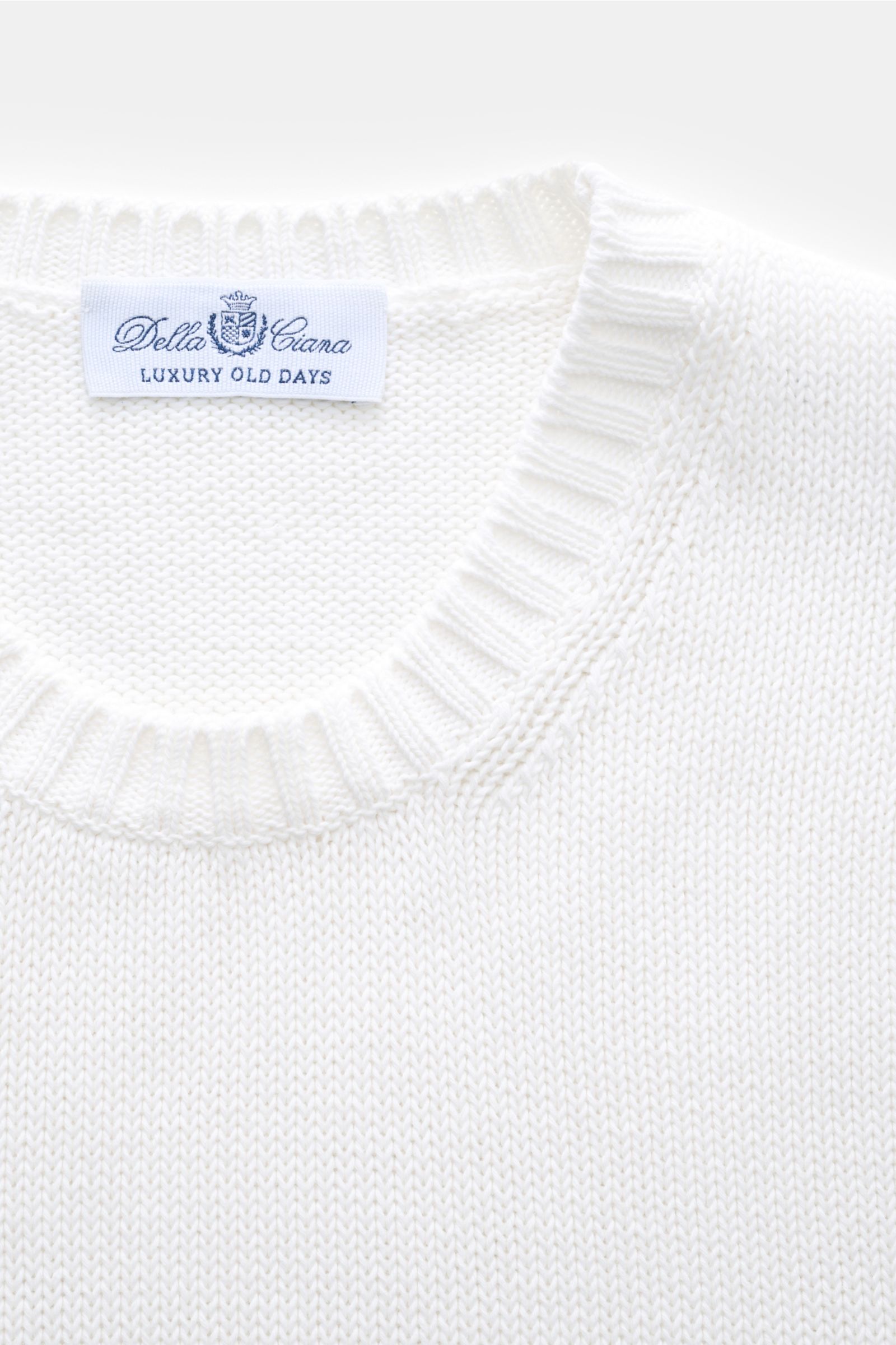 Close-up front view of the white Della Ciana Crew neck jumper showing ribbed crew neckline and label.

This elegant Italian cotton jumper by DELLA CIANA will enhance your spring wardrobe with its classic fit and can be styled in a variety of ways to cr