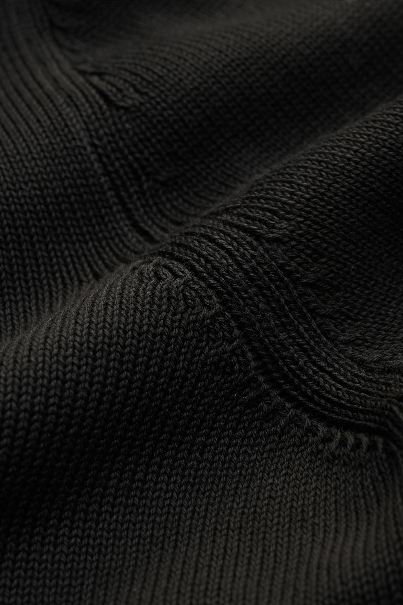 Nahaufnahme des fein gestrickten Gran Sasso Rundhalspullover schwarz aus reiner Baumwolle mit weichem Griff, Slim Fit, Rundhalsausschnitt und Rippbündchen, fotografiert aus leicht seitlicher Perspektive.