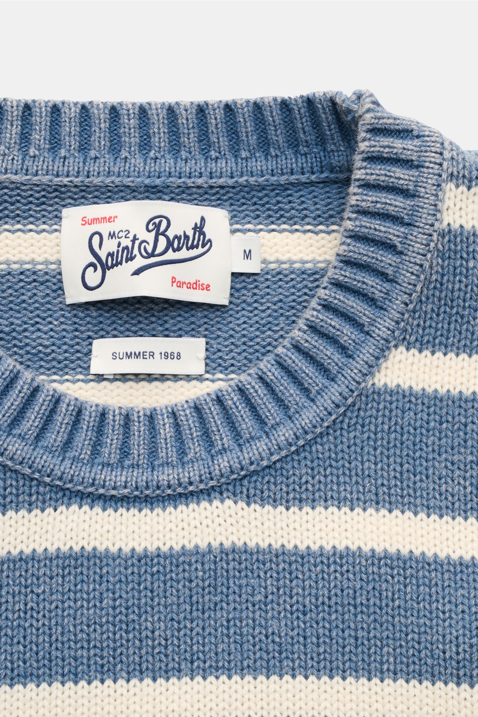 Close-up front view of the MC2 Saint Barth Crew neck jumper 'Sydney Cotton' smoky blue/cream striped, showing ribbed crew neck and labels. Dancing barefoot on a table: The 'Sydney Cotton' crew neck jumper from MC2 Saint Barth captures the nostalgic spirit