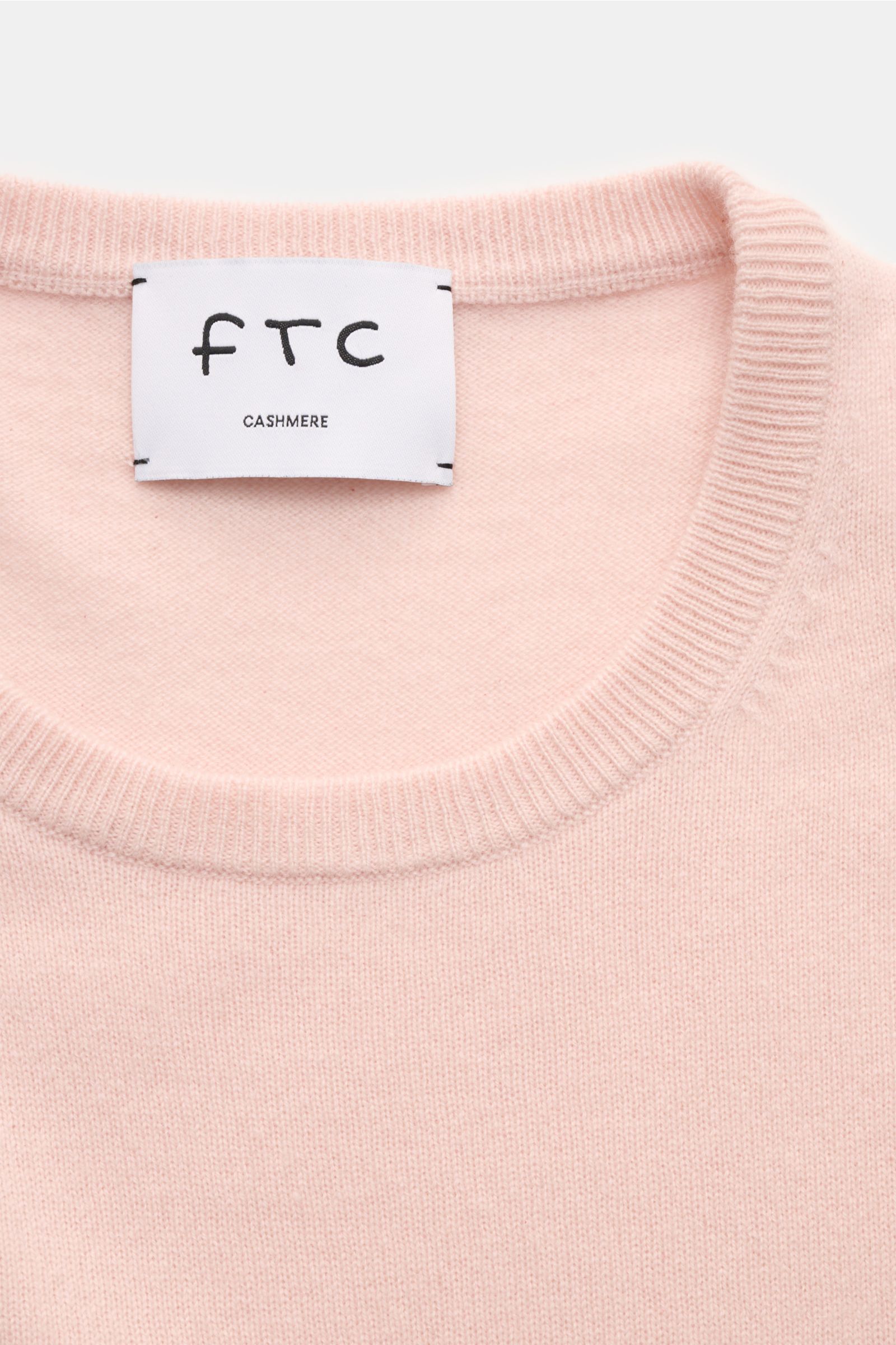 Nahaufnahme des FTC Cashmere Rundhalspullovers rosé von oben fotografiert, zeigt feines Strickbild, Slim Fit, Rundhalsausschnitt, komfortable Rippbündchen und ultraweiche, reine Cashmere-Qualität.