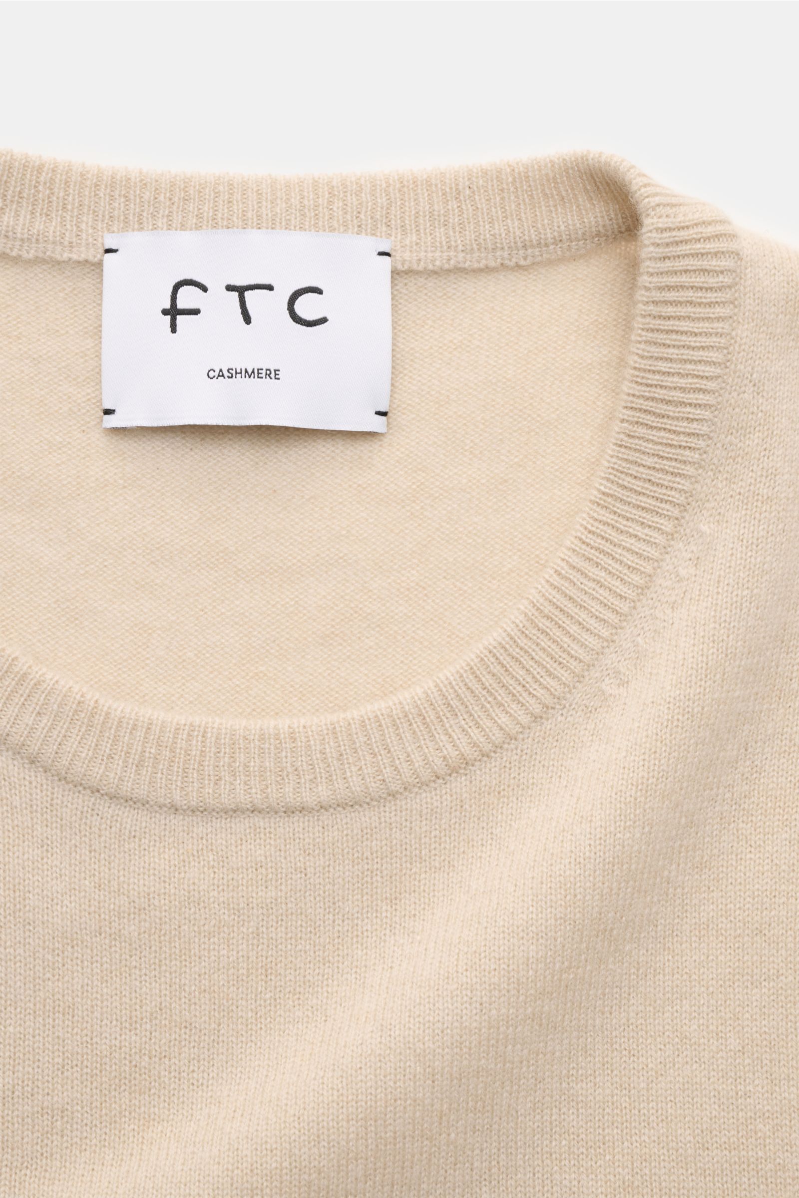 Nahaufnahme des FTC Cashmere Rundhalspullover beige mit feinem Strickbild, Slim Fit und komfortablen Rippbündchen, von oben fotografiert.