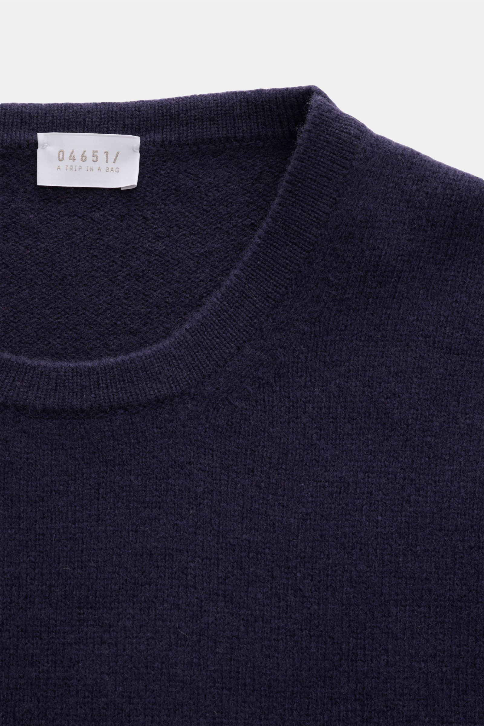 Close-up image of the neckline and upper chest of the 04651/ A trip in a bag Crew neck jumper 'Piping' navy, photographed from above, showing its fine knit, soft wool and cashmere blend with a regular fit, crew neck, and double-layered seams. Cosy and com