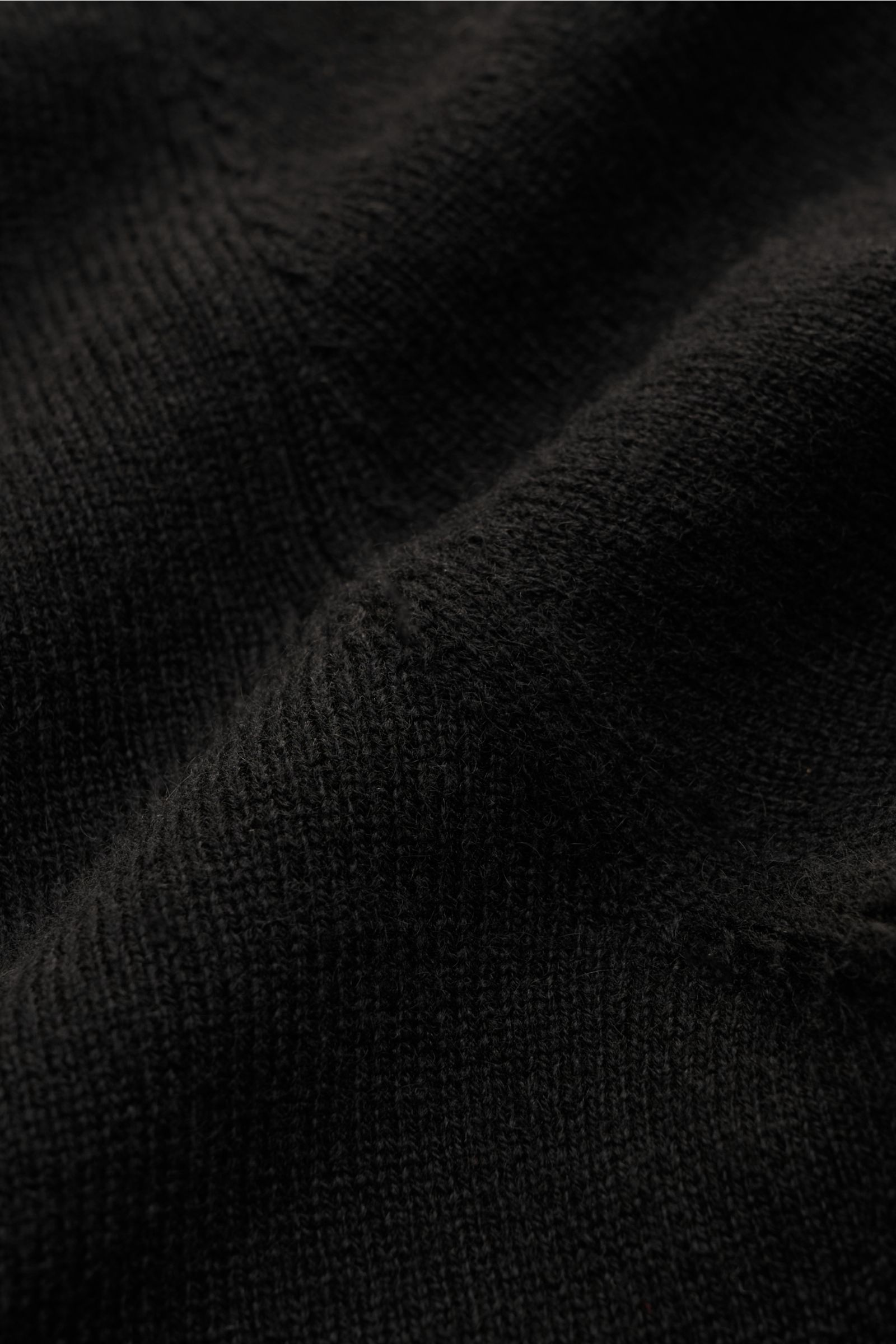 Nahaufnahme des feinen Strickbilds des von Braun Cashmere Rundhalspullover schwarz, Slim Fit mit weichem Griff, Rundhalsausschnitt, flexiblen Rippbündchen aus reinem mongolischem Cashmere – vielseitiges Essential für die kalte Jahreszeit.