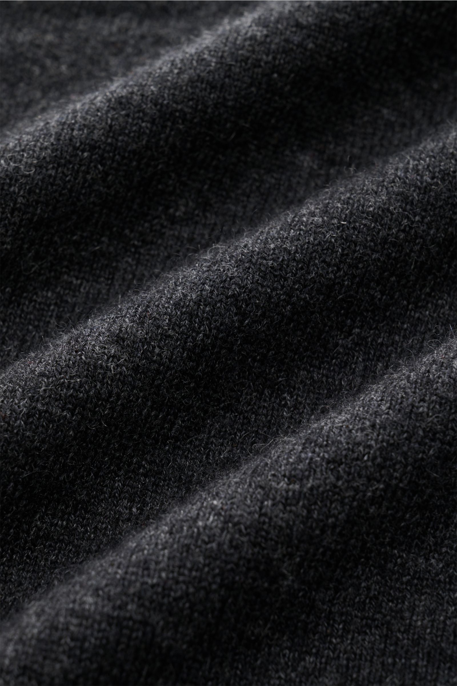 Nahaufnahme des feinen Strickbilds und weichen Griffs des von Braun Cashmere Rundhalspullover dunkelgrau meliert aus mongolischem Cashmere.