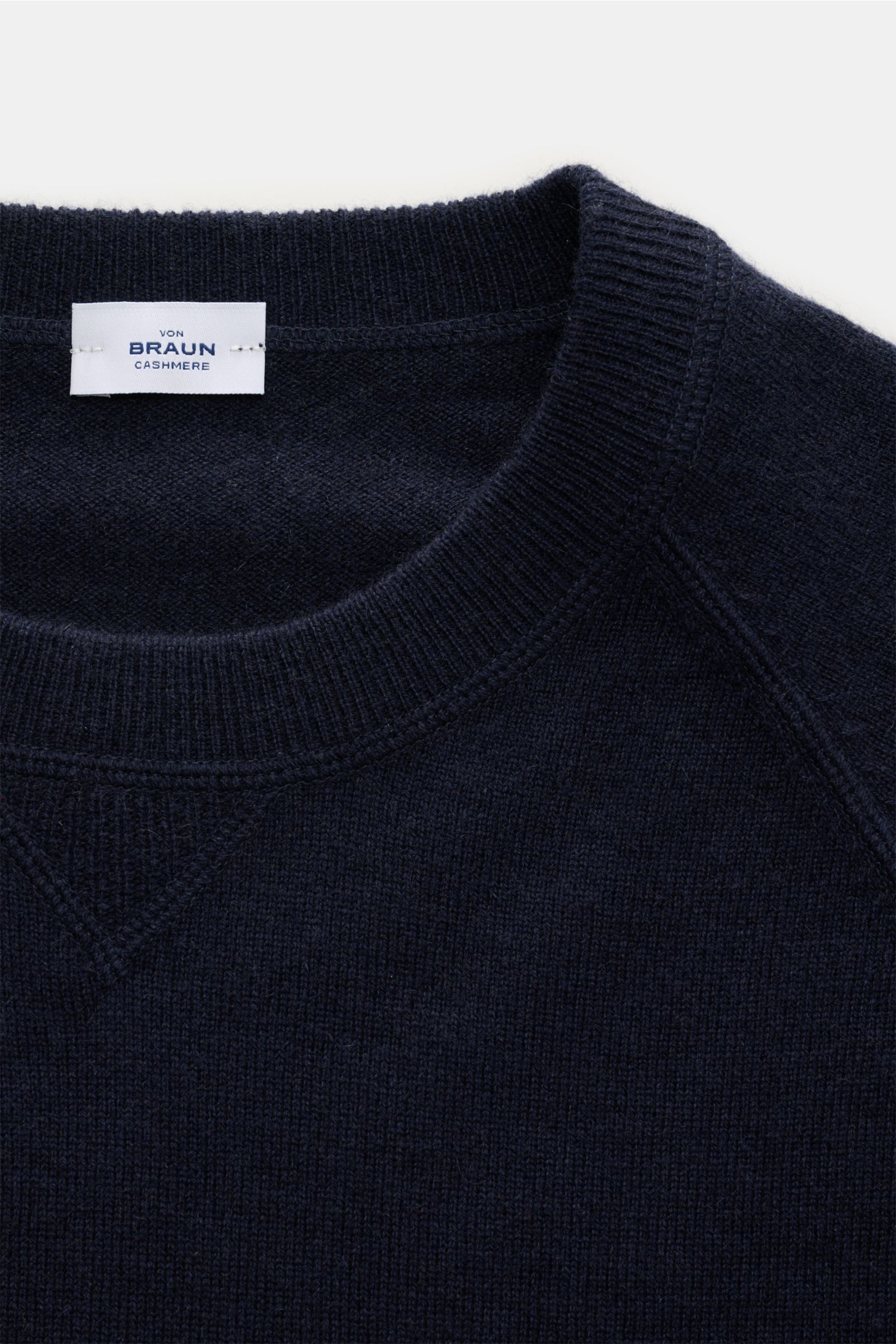 Nahaufnahme aus leicht schräger Draufsicht eines von Braun Cashmere Rundhalspullover navy mit Rundhalsausschnitt, Raglanärmeln, feinem Strickbild und weichem Griff.