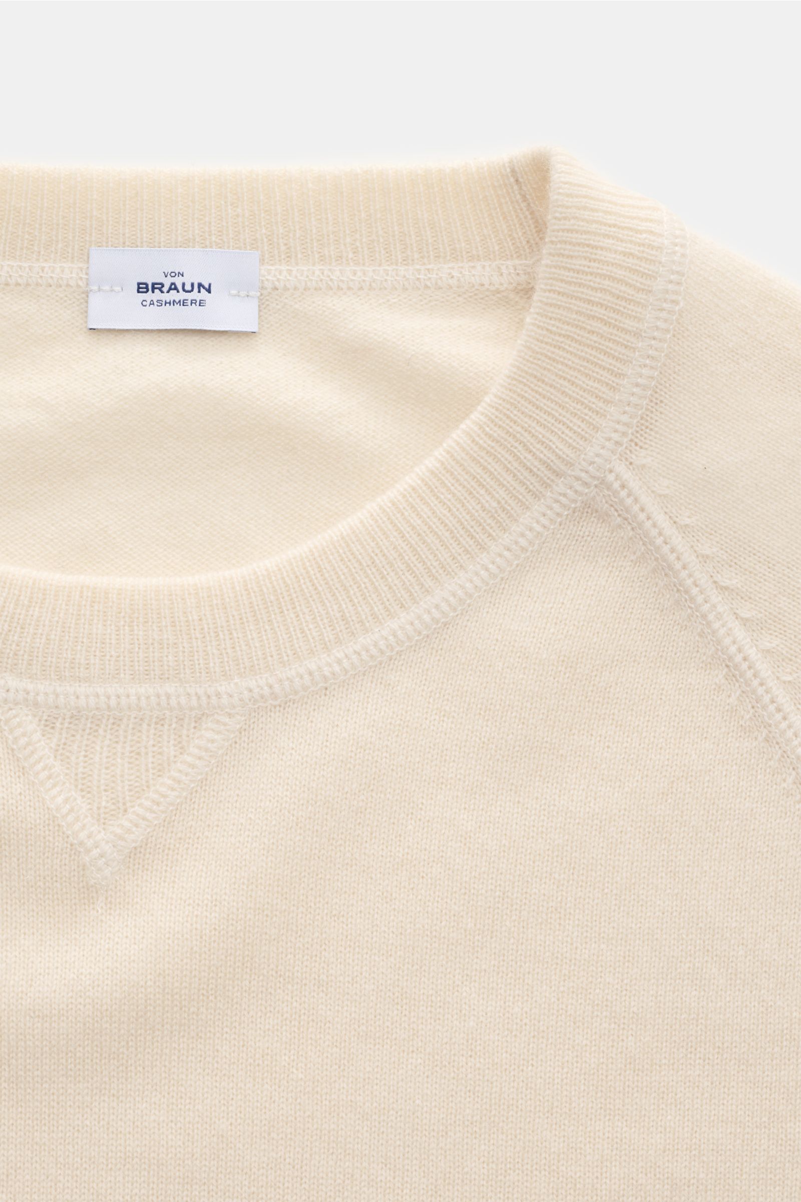 Nahaufnahme des von Braun Cashmere Rundhalspullover creme von oben, mit Rundhalsausschnitt, Raglanärmeln und feinem Strickbild aus reinem, weichem Cashmere.