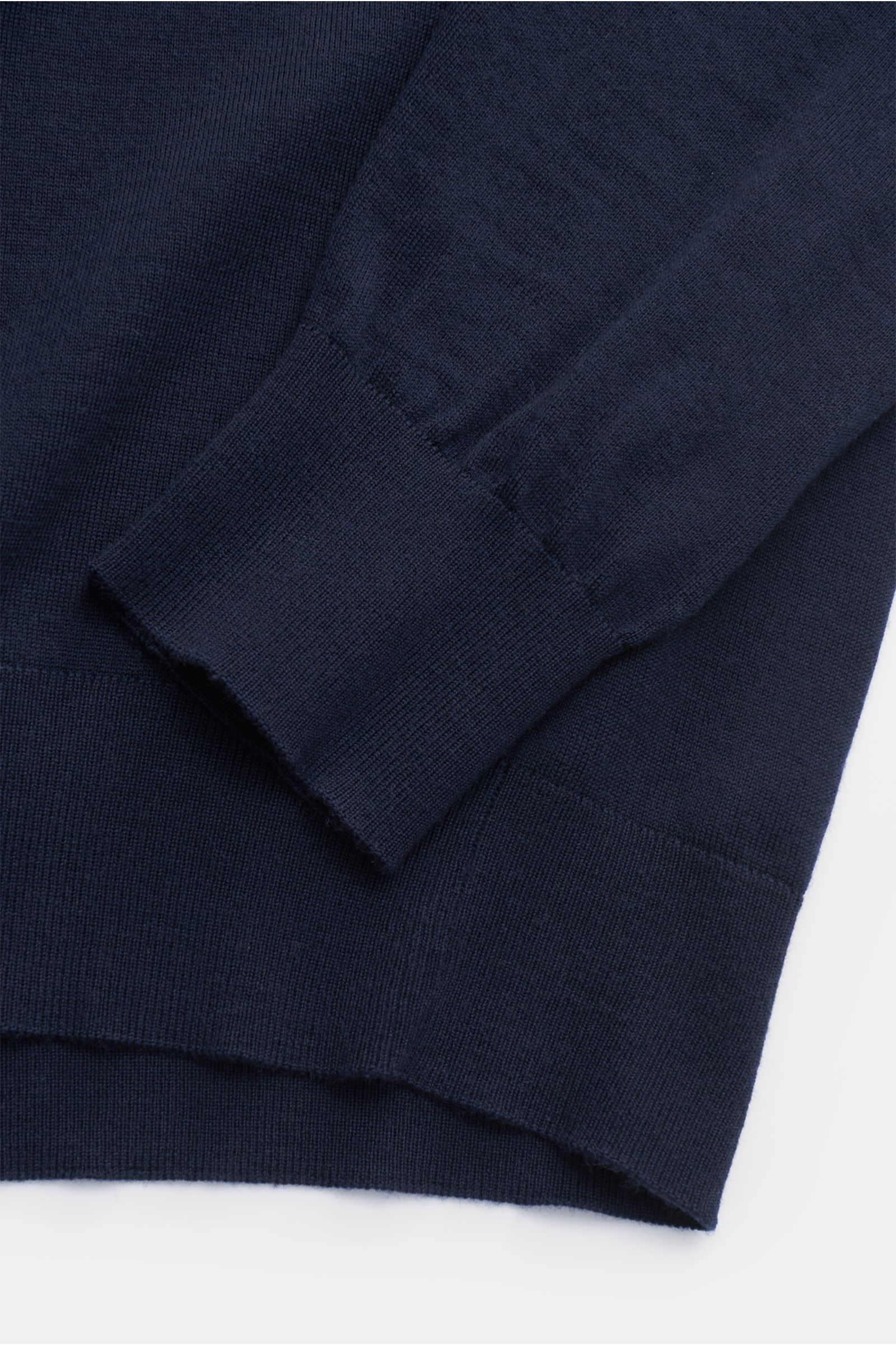 Nahaufnahme von Ärmel und Saum des von Braun Merino Rundhalspullover navy, edler Feinstrick aus reiner Merinowolle, Slim Fit, weicher Griff, feines Strickbild, Rundhalsausschnitt, elastische Rippbündchen, fotografiert aus seitlicher Perspektive.