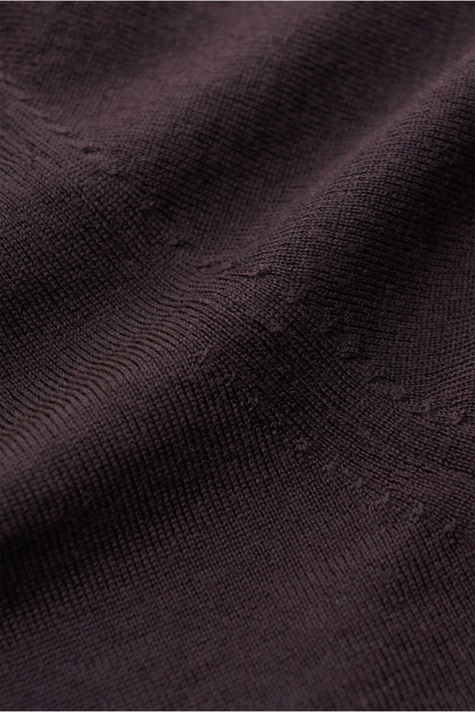 Nahaufnahme aus schräger Perspektive des von Braun Merino Rundhalspullover dunkelbraun mit feinem Strickbild, weichem Griff, Slim Fit, Rundhalsausschnitt und elastischen Rippbündchen aus reiner Merinowolle.