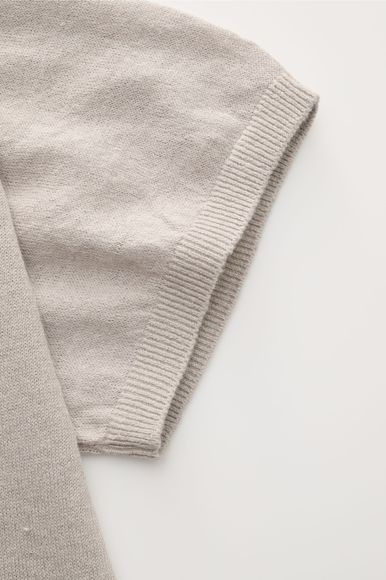 Nahaufnahme der Ärmelpartie des 04651/ A trip in a bag Feinstrick-Kurzarmpullover 'Pocket Tee' taupe aus Leinen-Baumwoll-Mix mit feinem Strickbild, Rundhalsausschnitt und komfortablem Bündchen, fotografiert von oben.