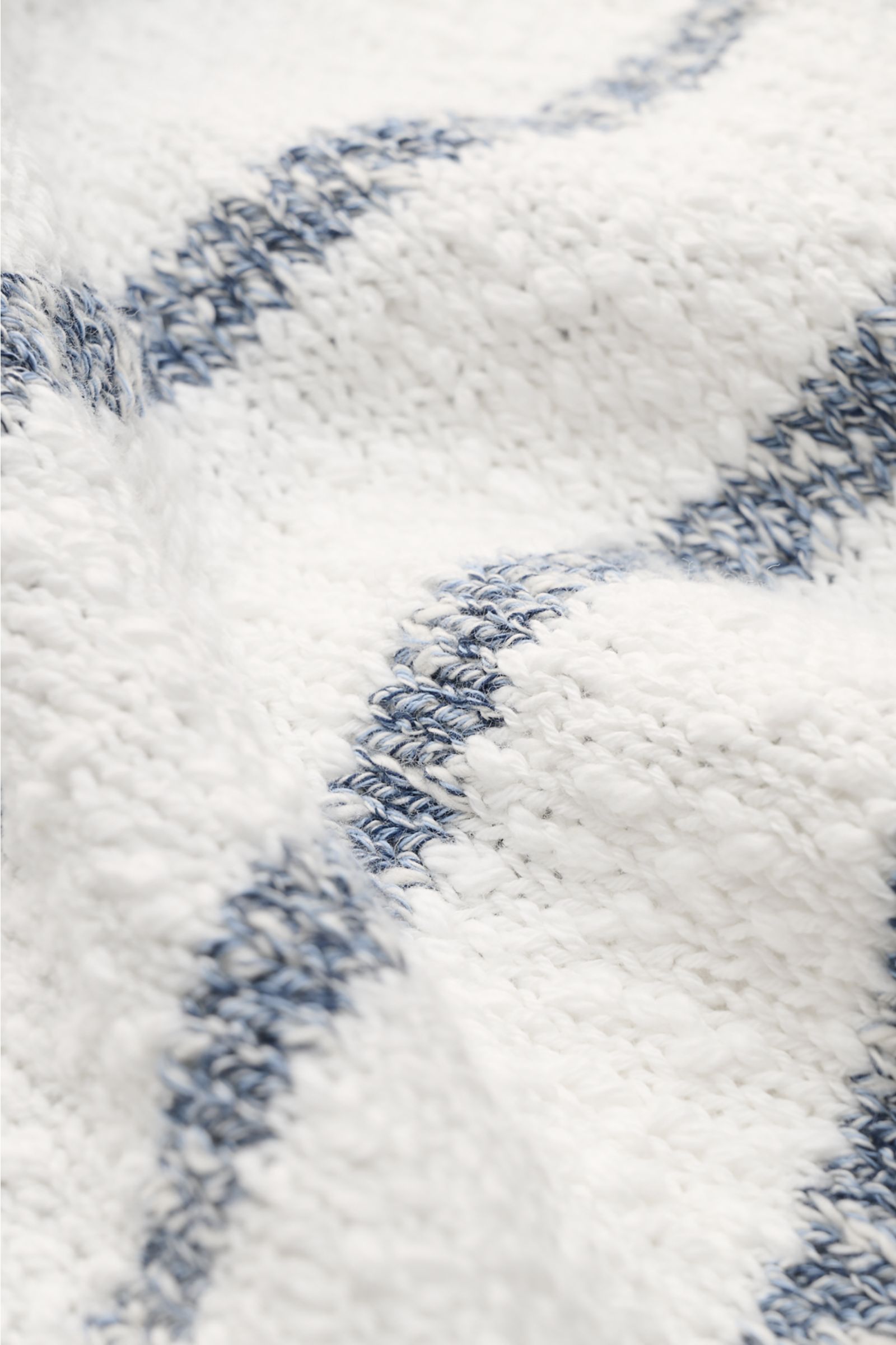 Nahaufnahme des grob gestrickten 04651/ A trip in a bag Rundhalspullover 'Mouline Striped' offwhite/navy gestreift mit klassischem Streifenmuster, Rundhalsausschnitt und Rippbündchen aus reiner Baumwolle, perspektivisch von oben fotografiert.