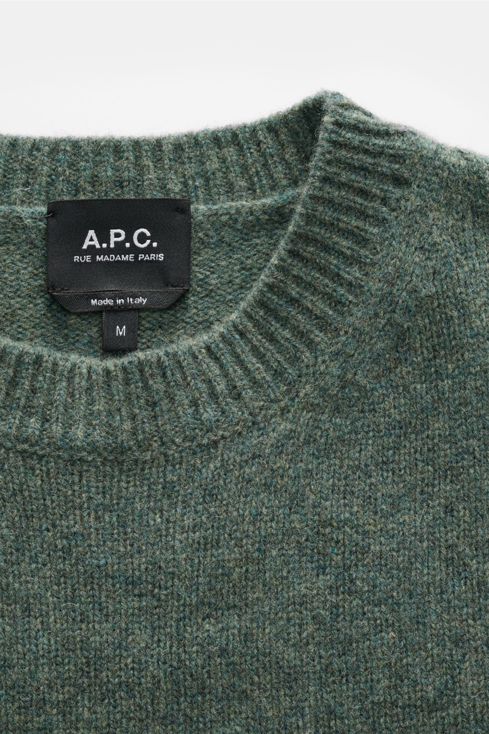 Nahaufnahme des Rundhalsausschnitts und Labels des A.P.C. Rundhalspullover 'Edmond' graugrün meliert aus reiner Wolle.