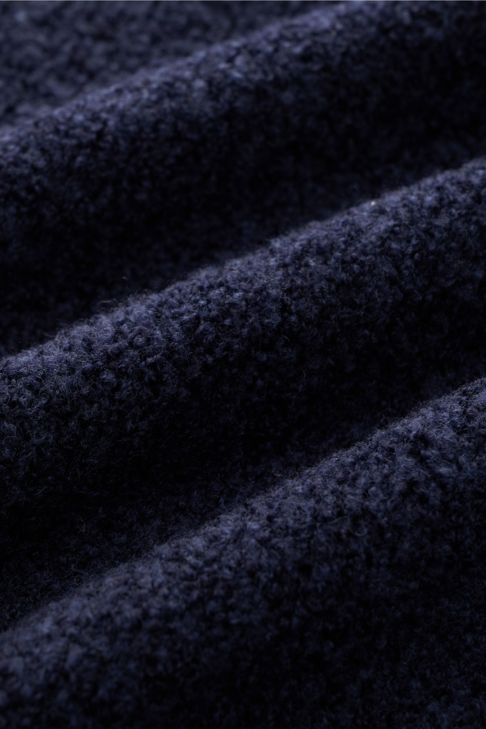 Close-up front view of the 04651/ A trip in a bag Mock neck jumper 'Grainy' navy melange showing its soft, boucle knit wool blend fabric texture. For modern looks: The jumper 'Grainy' by 04651/ A TRIP IN A BAG is made of a warm wool blend in bouclé knit t
