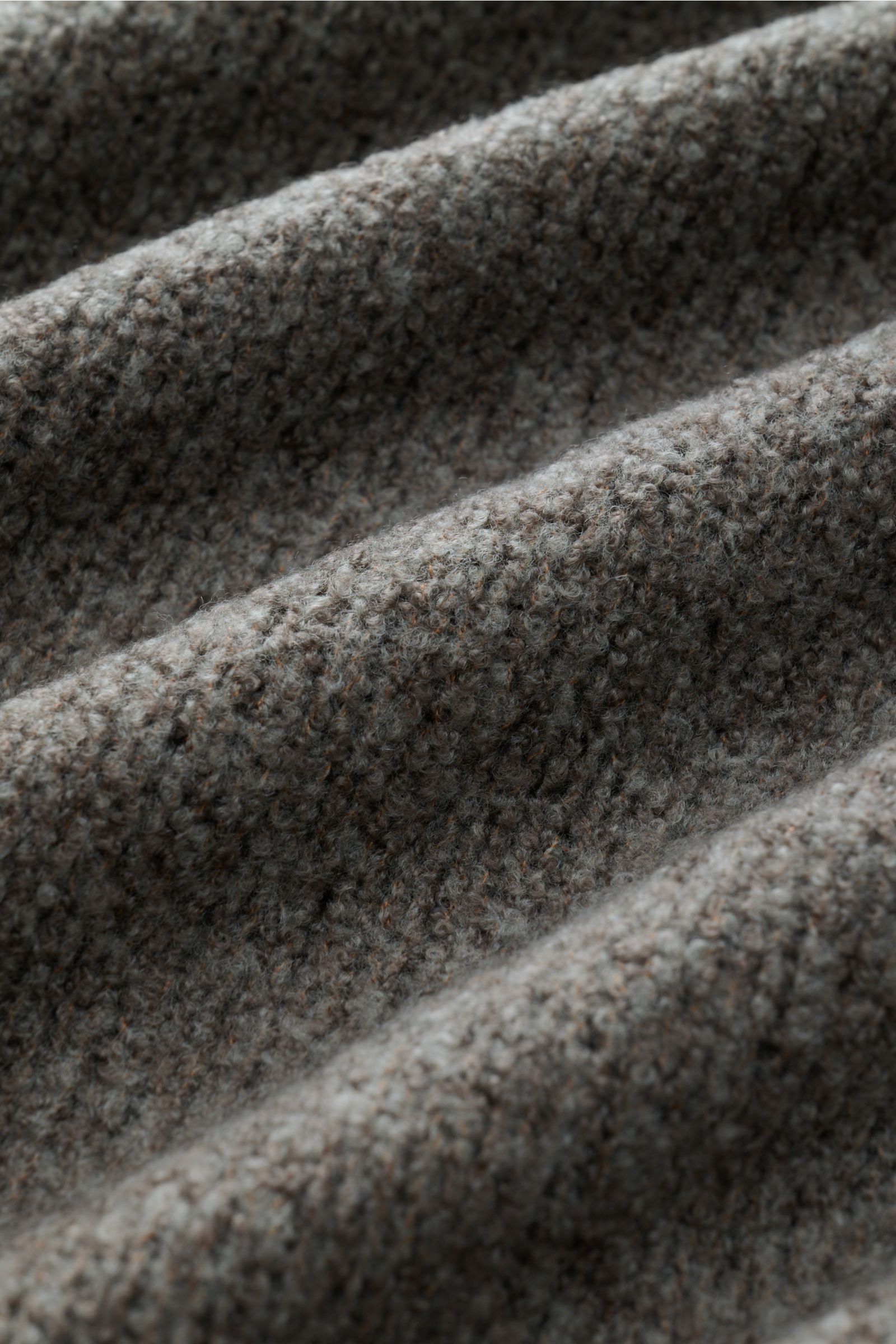 Close-up image showing the texture and detail of the 04651/ A trip in a bag Mock Neck Pullover 'Grainy' taupe, photographed from a top angle. Für moderne Looks: Der Pullover 'Grainy' von 04651/ A TRIP IN A BAG wurde aus wärmendem Woll-Mix im Boucléstrick 