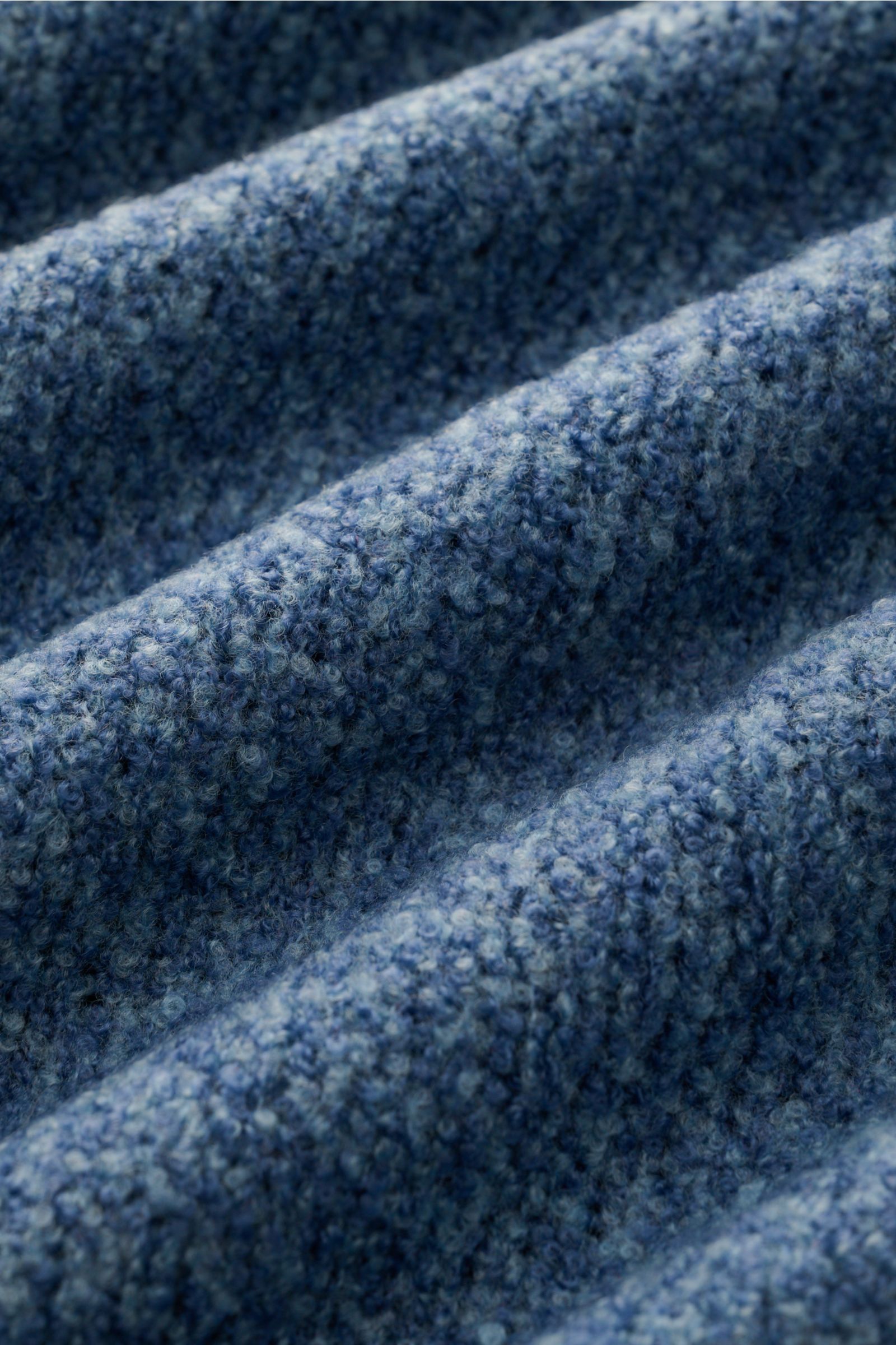 Close-up, angled view of the boucle knit fabric in smoky blue of the 04651/ A trip in a bag Mock Neck Pullover 'Grainy'. Für moderne Looks: Der Pullover 'Grainy' von 04651/ A TRIP IN A BAG wurde aus wärmendem Woll-Mix im Boucléstrick gefertigt und bringt 