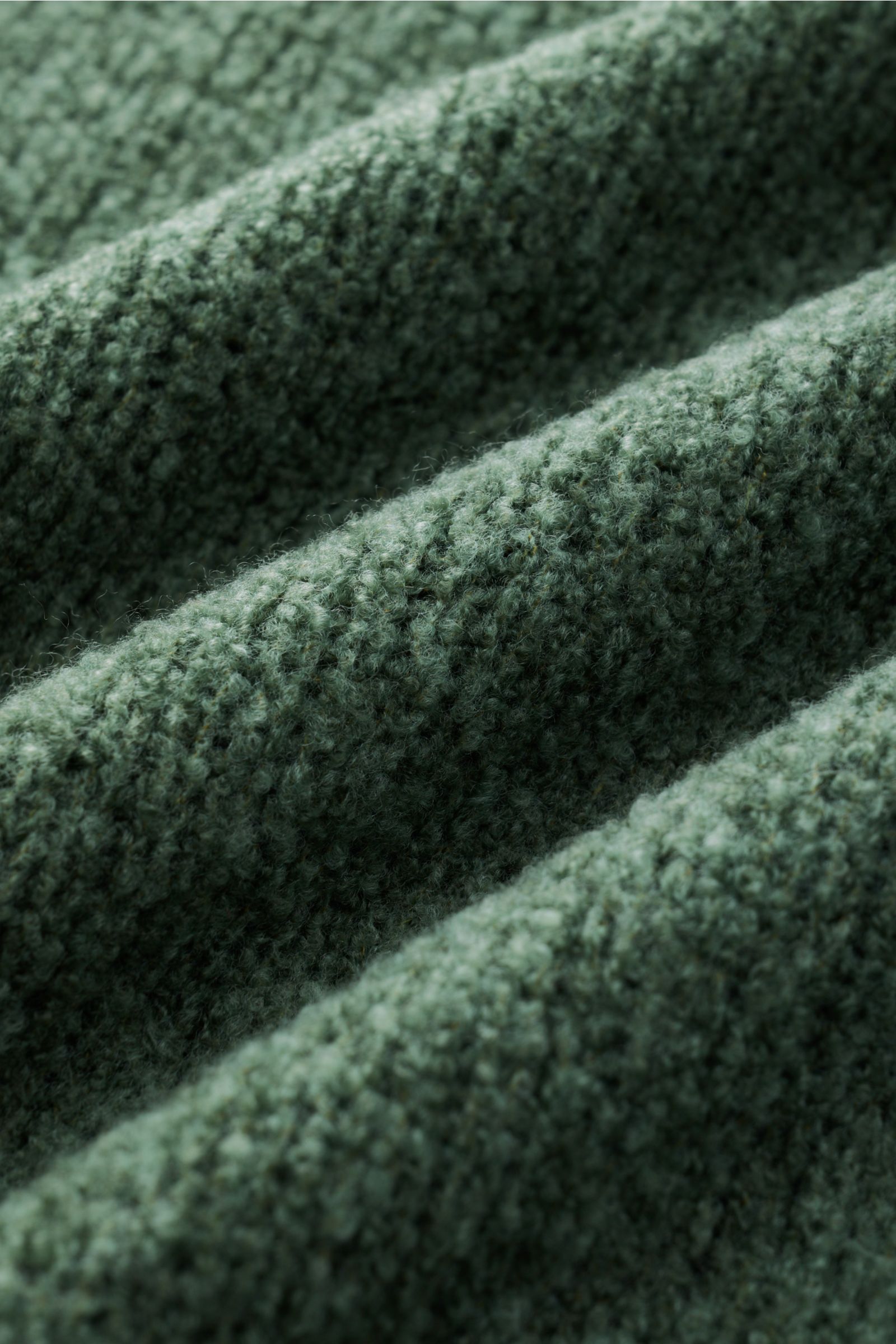 Makroaufnahme des grünen 04651/ A trip in a bag Mock Neck Pullovers 'Grainy' mit wärmendem Woll-Mix, weichem Boucléstrick und mittelfeinem Strickbild.