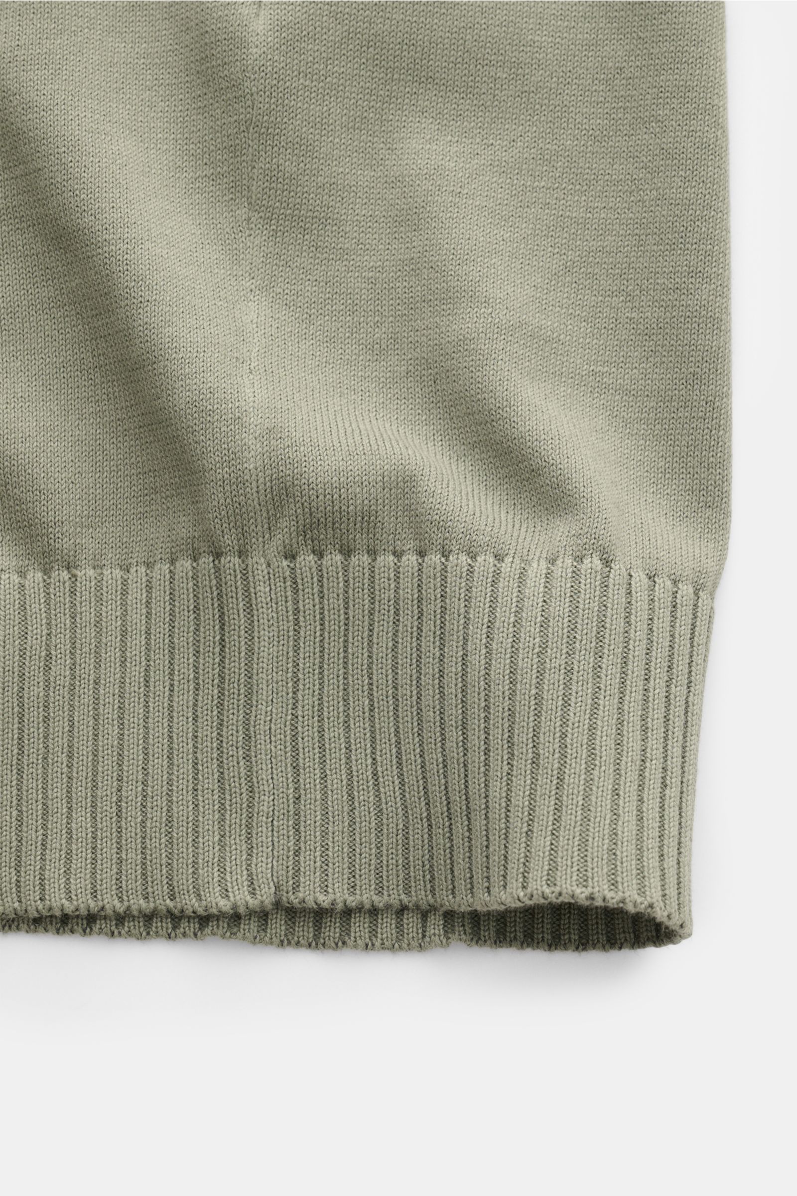 Nahaufnahme des unteren Saums mit komfortablem Rippbündchen des Malo Kurzarmpullover grün aus reiner Baumwolle, feines Strickbild, Regular Fit.