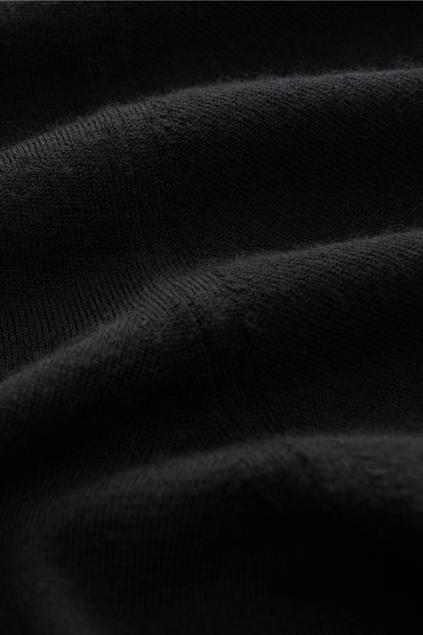 Nahaufnahme des schwarzen Colombo Rundhalspullover aus Kid Wool, zeigt feine Strickstruktur, weichen Griff und Rippbündchen.