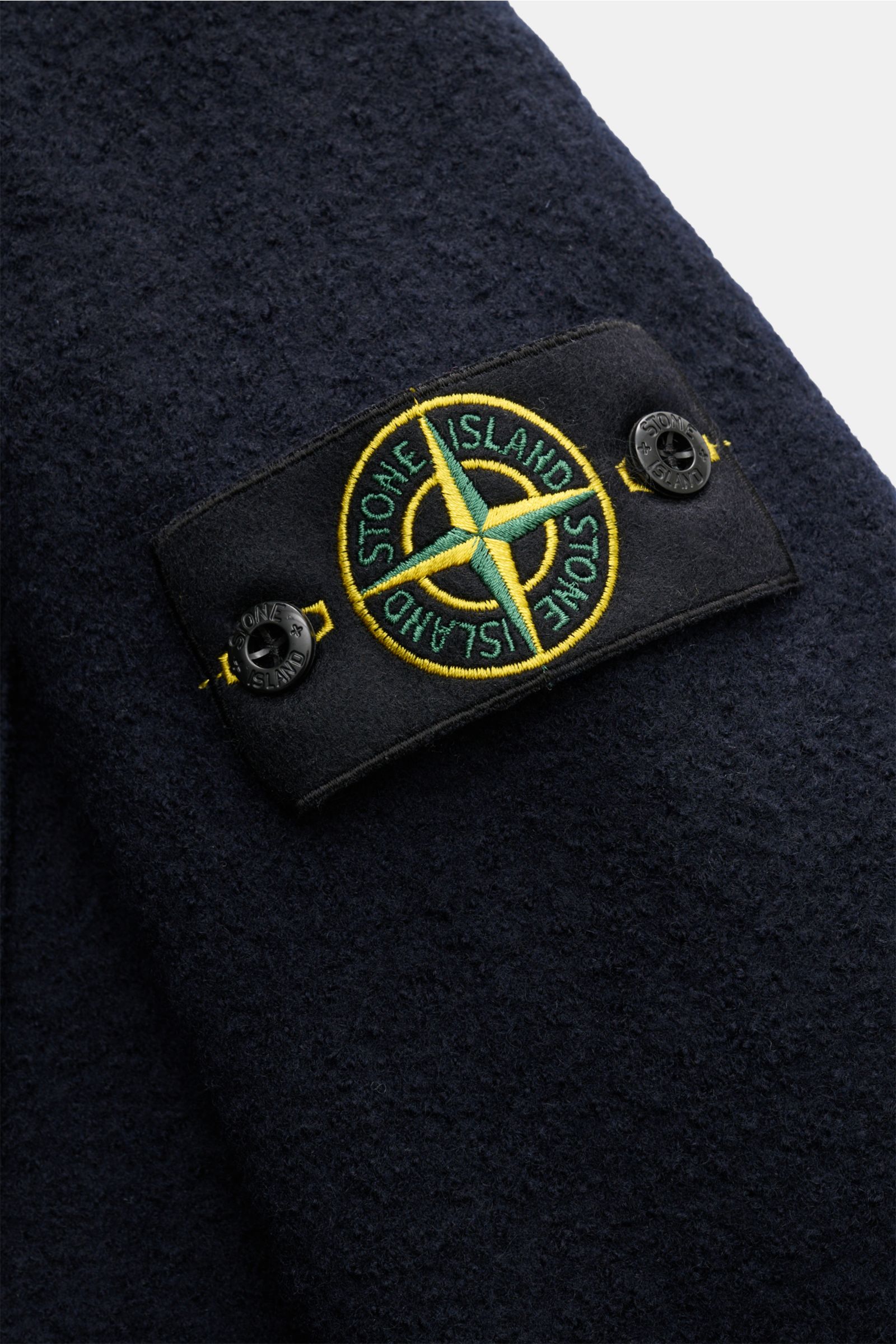 Close-up view of the Stone Island Overshirt navy showing the typical compass badge on the sleeve, made of reine, gefilzte Wolle, with a soft touch, garment dyed, Regular Fit, Druckknopfleiste, Umlegekragen, and aufgesetzte Brusttaschen.