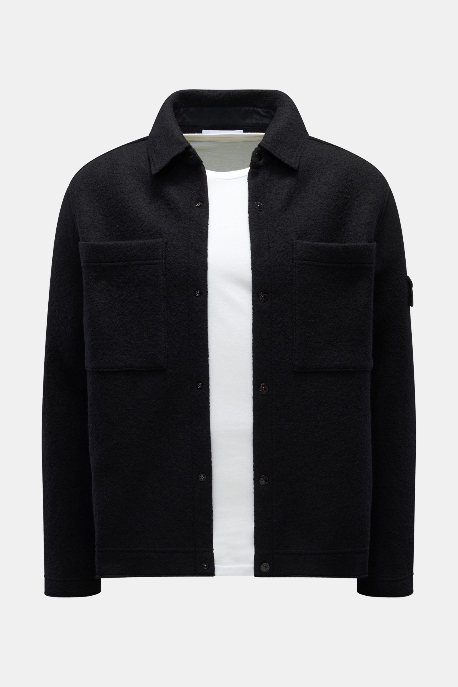 Front view of Stone Island Overshirt schwarz in black, made of reine, gefilzte Wolle with weicher Griff, garment dyed, Regular Fit, Druckknopfleiste, Umlegekragen, aufgesetzte Brusttaschen, and typisches Kompass-Badge am Ärmel.