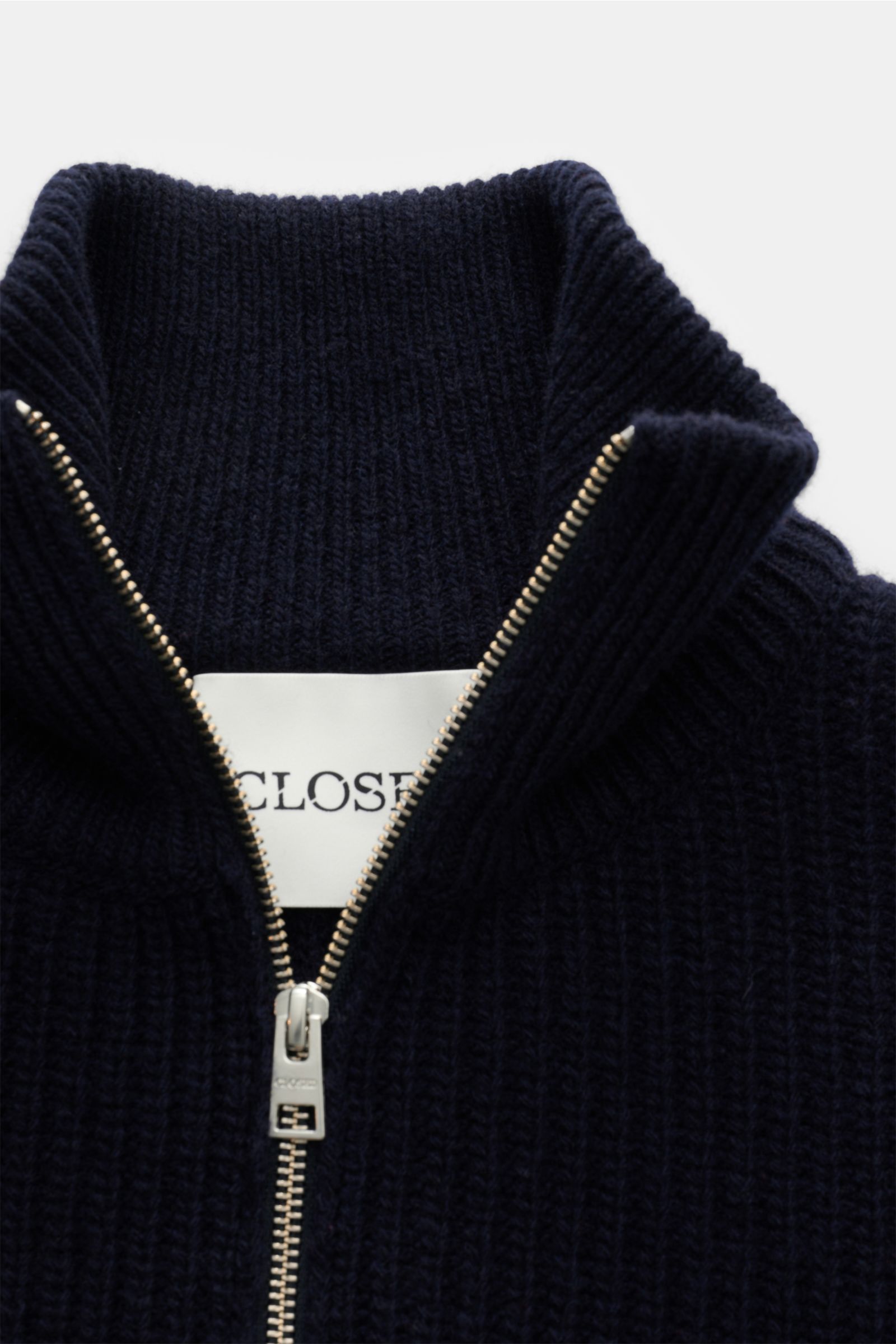 Nahaufnahme des Closed Troyer navy von oben fotografiert, Patentstrick aus reiner Wolle, schwere Qualität, grobes Strickbild, leicht griffige Haptik, Regular Fit, Rippstrickkragen mit Zipper, breite Rippbündchen.