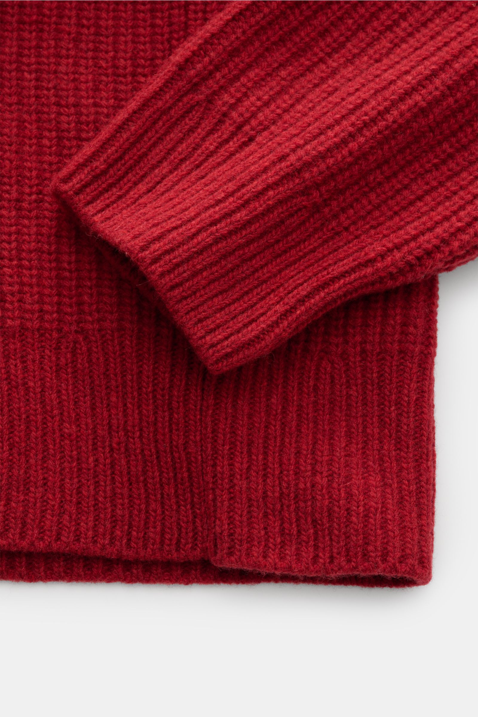 Close-up image of the sleeve and hem of the Closed Troyer rot, photographed from a top-down perspective showing the texture. Patentstrick aus reiner Wolle, schwere Qualität, grobes Strickbild, leicht griffige Haptik, Regular Fit, Rippstrickkragen mit Zipp