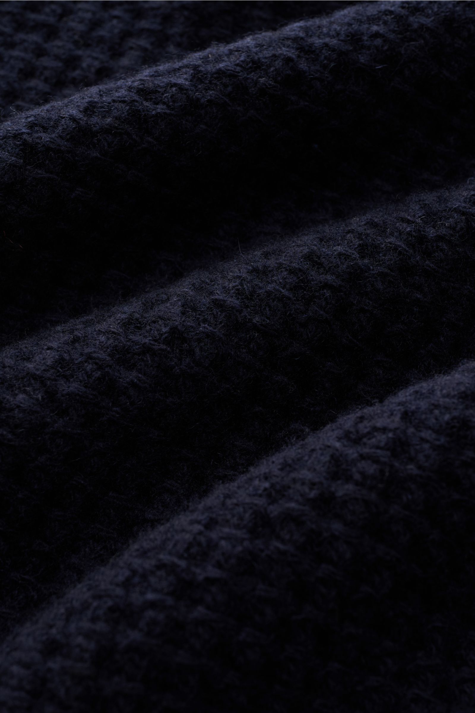 Close-up from a side angle of the Closed Strickpolo navy showing its textured coarse waffle knit in pure wool with a grippy, voluminous quality. Ein Strickpolo in neuem Gewand: Mit grobem Waffelstrick aus reiner Wolle und einer griffigen, voluminösen Q