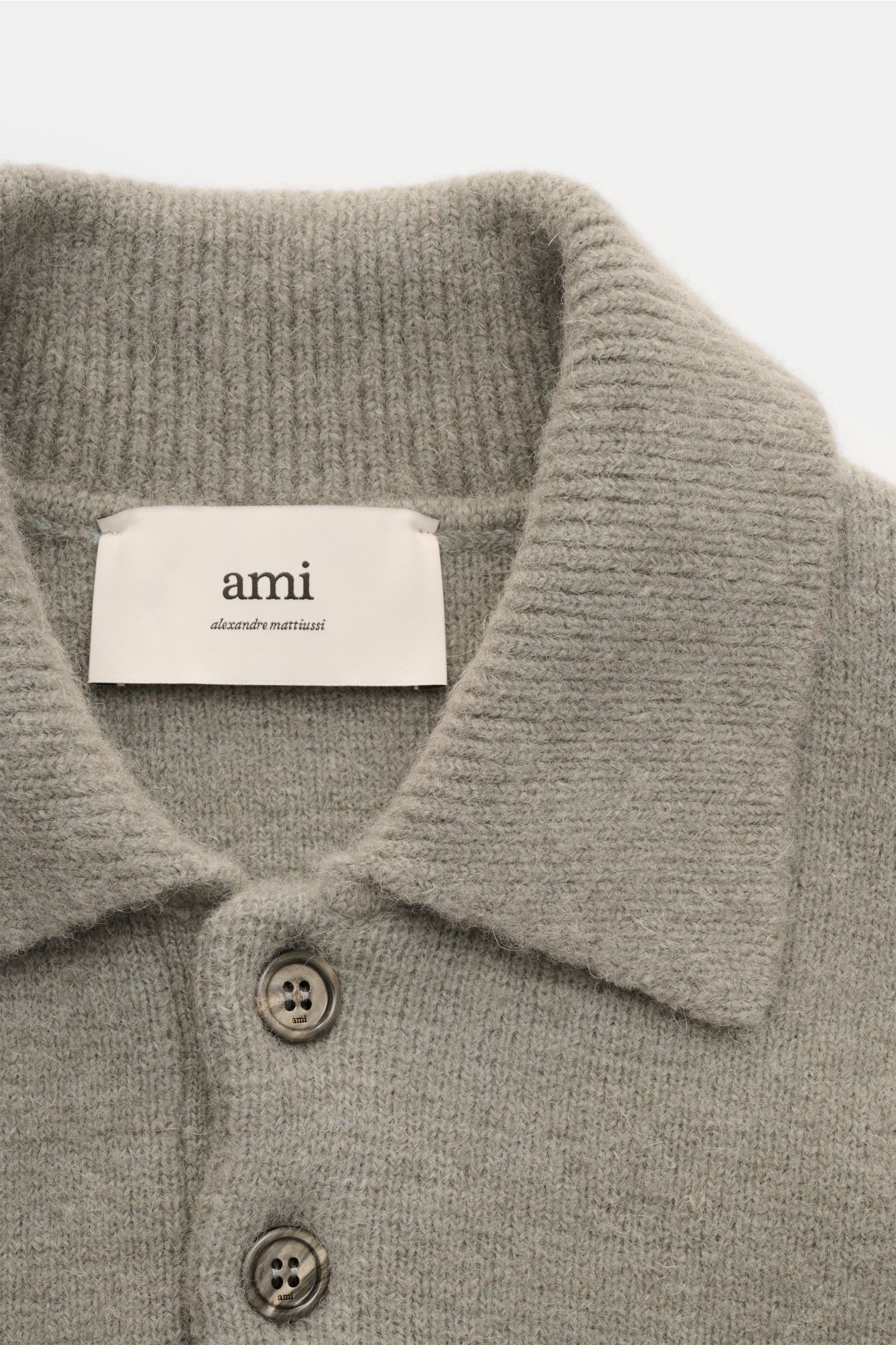 Close-up front view of Ami Paris Strickpolo grau showing soft alpaca blend knit, oversized fit, polo collar, three-button placket, and ribbed texture. Legerer Luxus für kalte Tage: AMI PARIS interpretiert das Strickpolo mit großem Herz-Logo in einer edlen