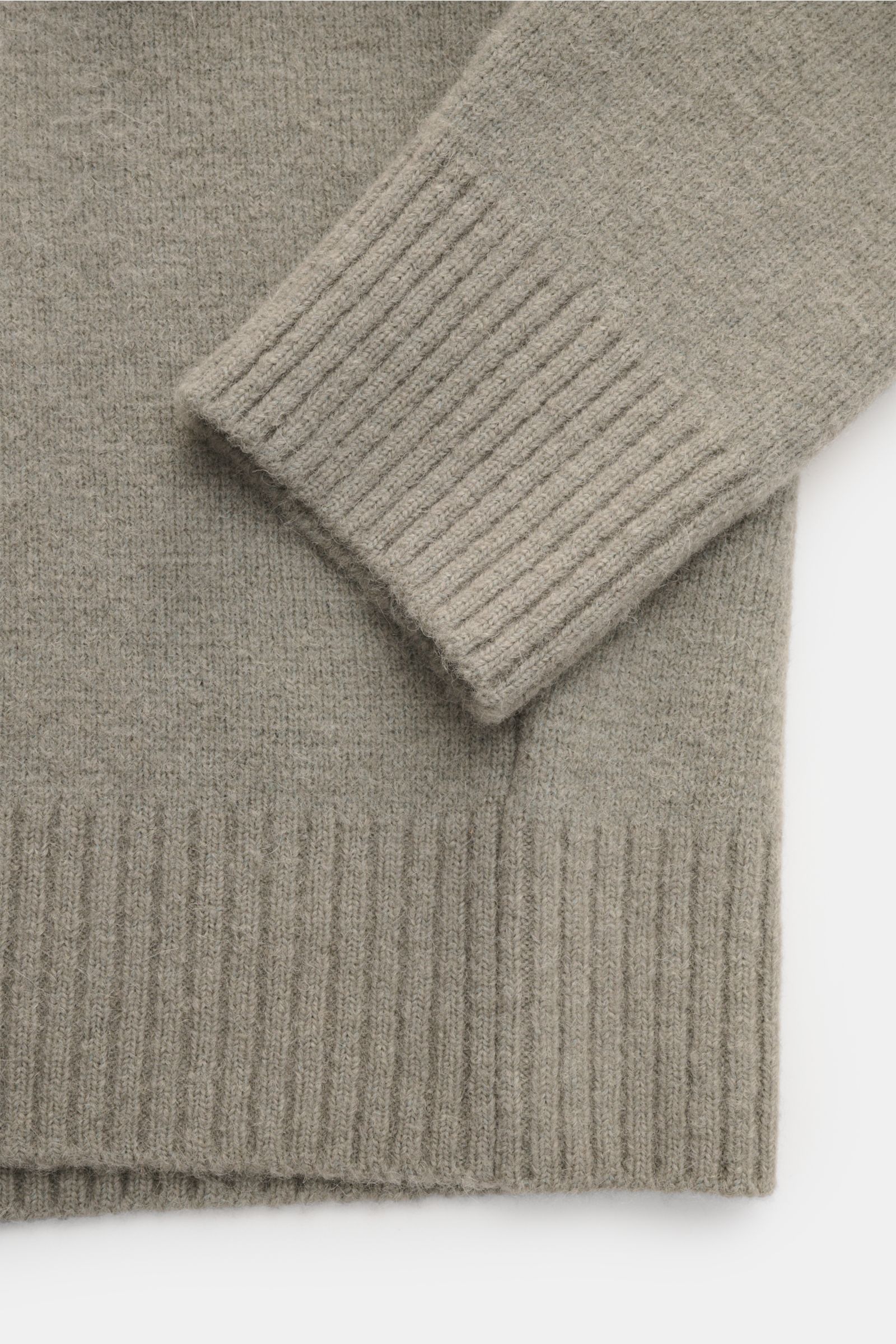 Close-up top view of Ami Paris Strickpolo grau sleeve and hem, showing soft alpaca-wool knit texture with ribbed cuffs and waistband, warm and oversized.

Legerer Luxus für kalte Tage: AMI PARIS interpretiert das Strickpolo mit großem Herz-Logo in eine