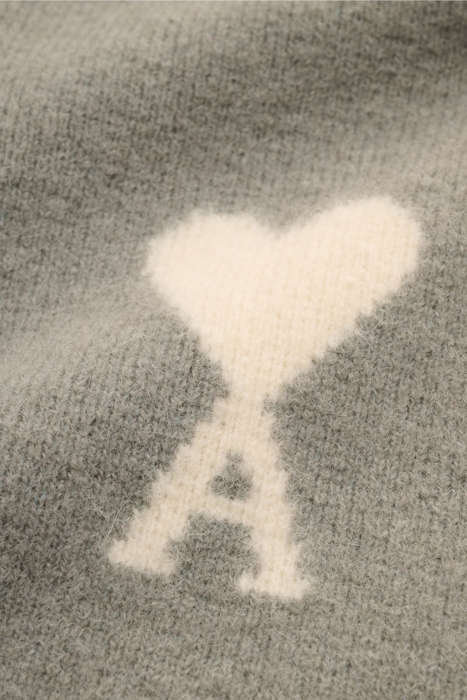 Close-up front view of Ami Paris Strickpolo grau knitwear showing the soft alpaca-wool blend fabric with a white heart and A logo knit into the grey oversized polo collar sweater.  

Legerer Luxus für kalte Tage: AMI PARIS interpretiert das Strickpolo 