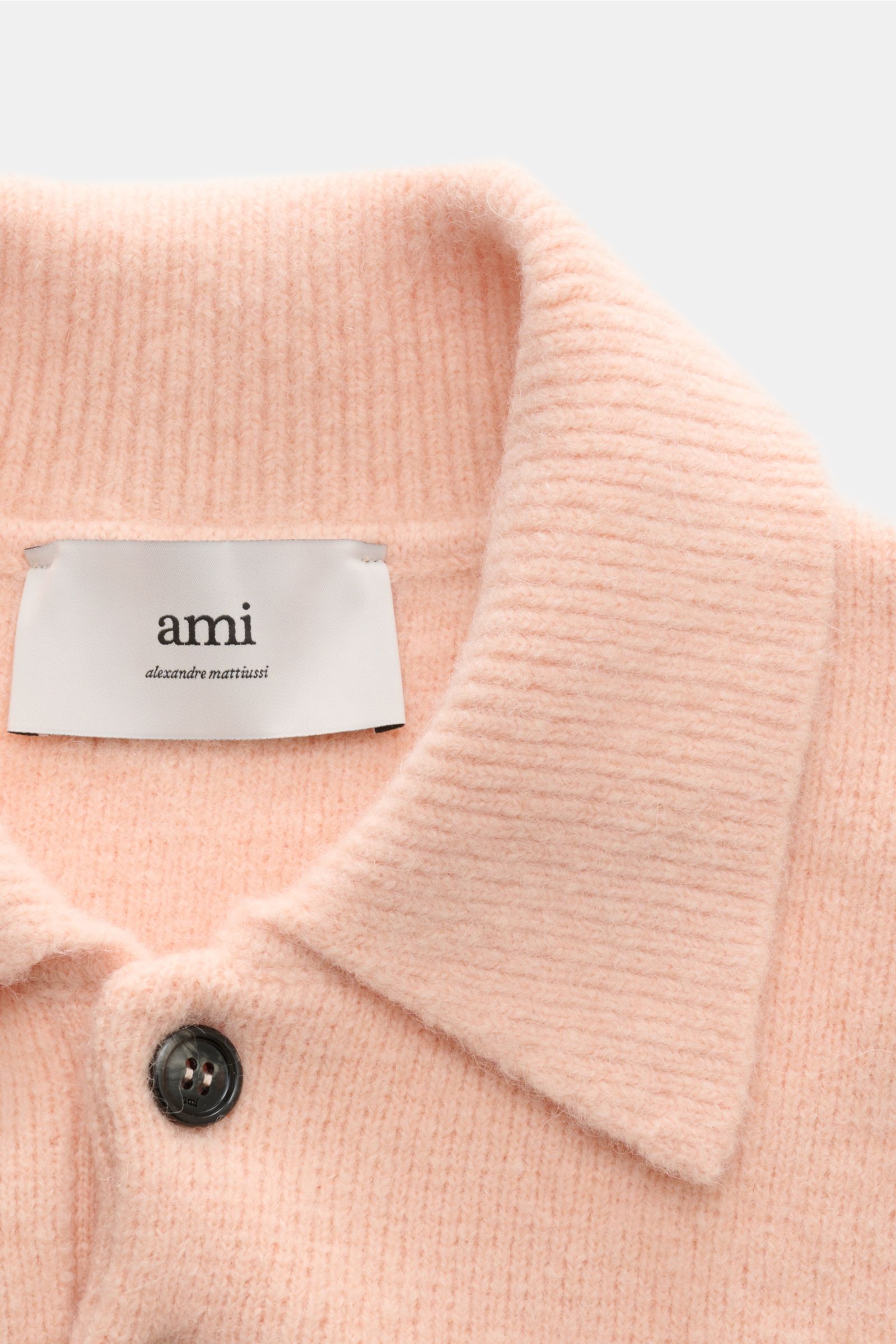 Ami Paris Strickpolo rosé in Nahaufnahme von oben, Polokragen, Knopf, weicher Alpaka-Wollmix, voluminöser Oversized Fit, eingestricktes Herz-Logo.