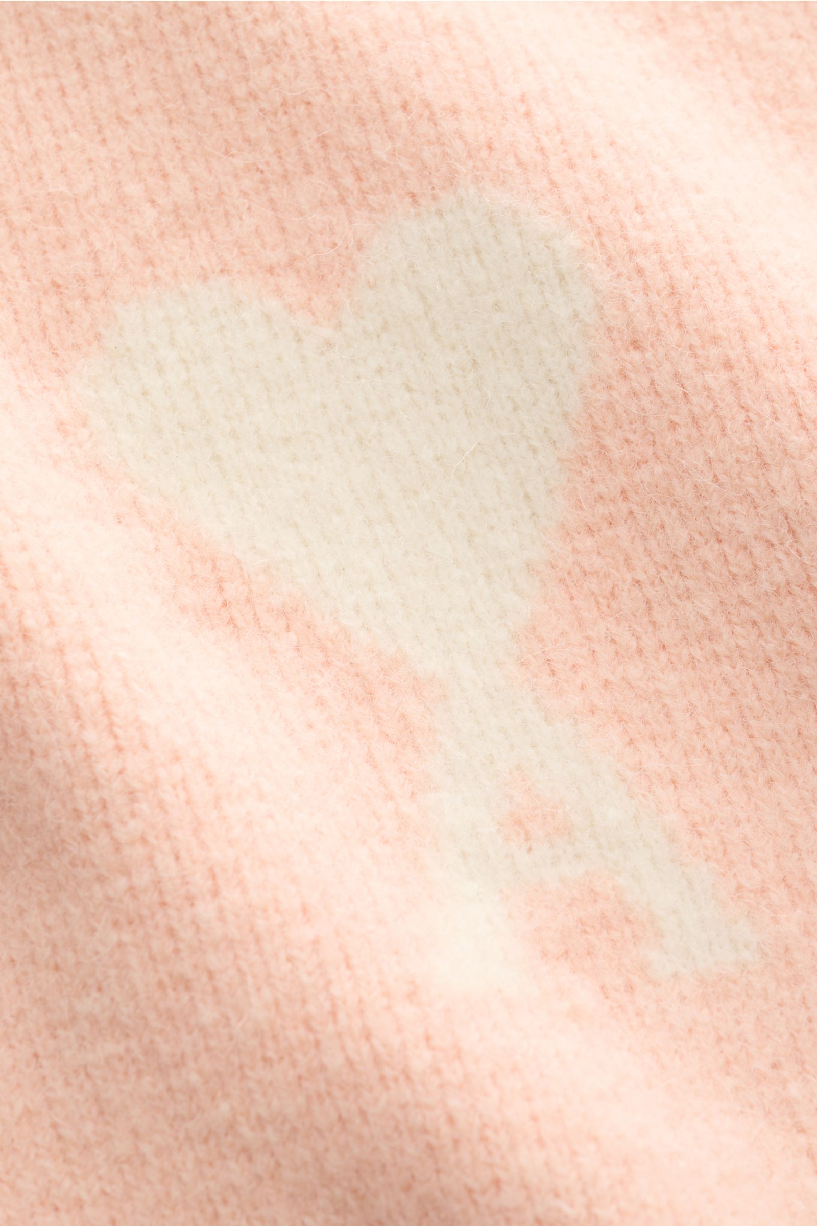 Nahaufnahme des Ami Paris Strickpolo rosé mit großem, eingestricktem weißen Herz-Logo, voluminösem Alpaka-Wollstrick, weichem Griff.