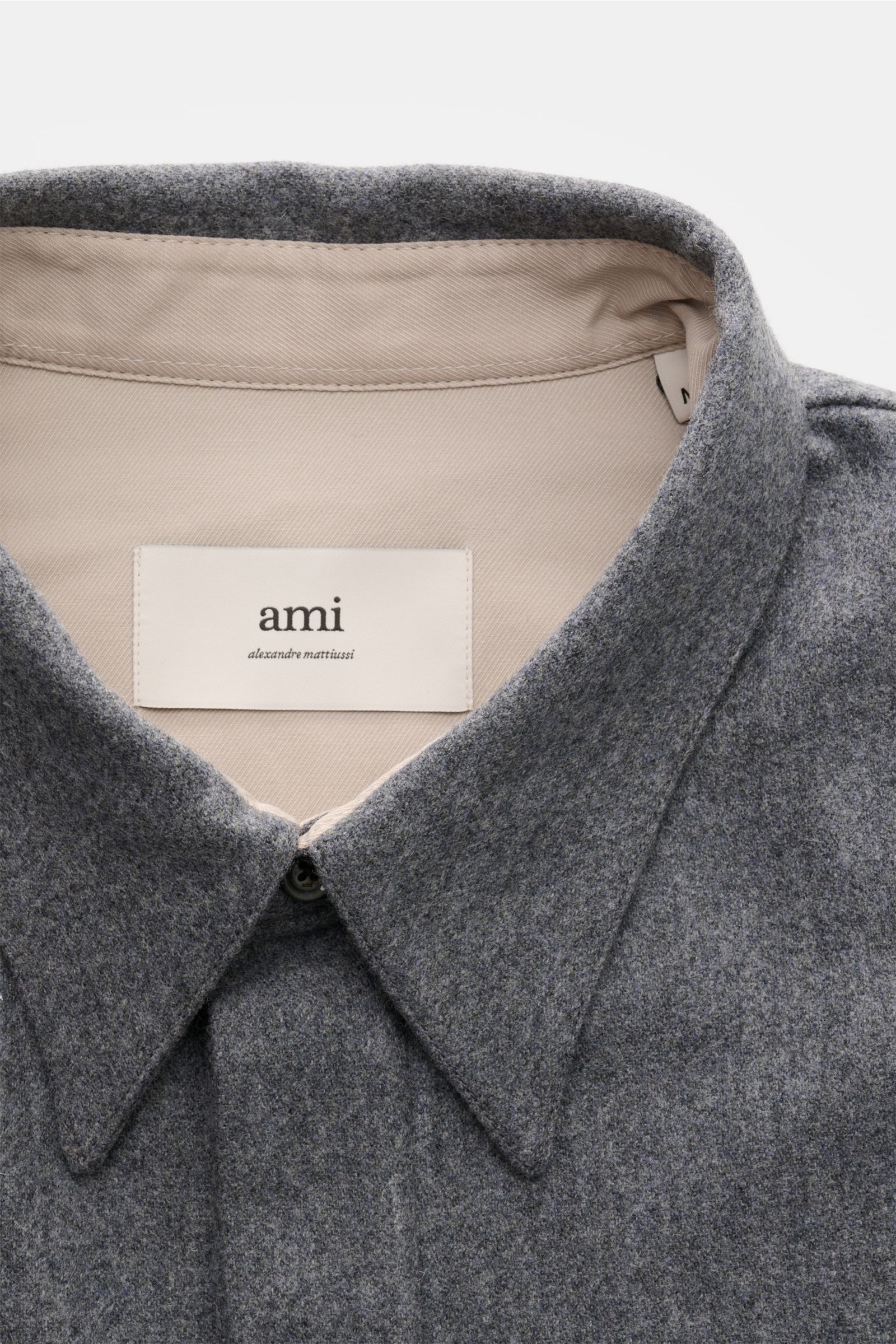 Close-up front view of Ami Paris Popover-Flanellhemd Kent-Kragen grau meliert in grey wool flannel with Kent collar, concealed placket, and beige inner lining.

Legerer Winter-Eyecatcher: Das Wollflanell-Hemd von AMI PARIS bietet mit seinem Oversized F