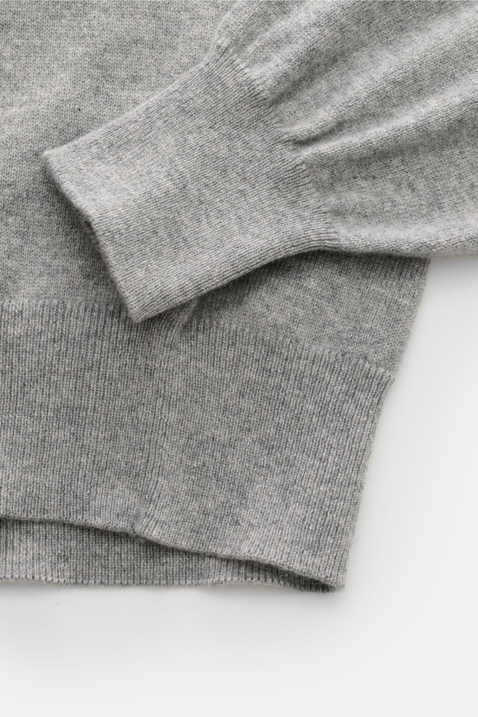 Close-up of the sleeve and hem of the Cruciani Cashmere Troyer grau meliert, showing fine knit and soft grey melange texture from a top-down perspective.

Durch die Verwendung feinster, geschmeidiger Cashmere-Garne entsteht bei CRUCIANI ein klassisch l