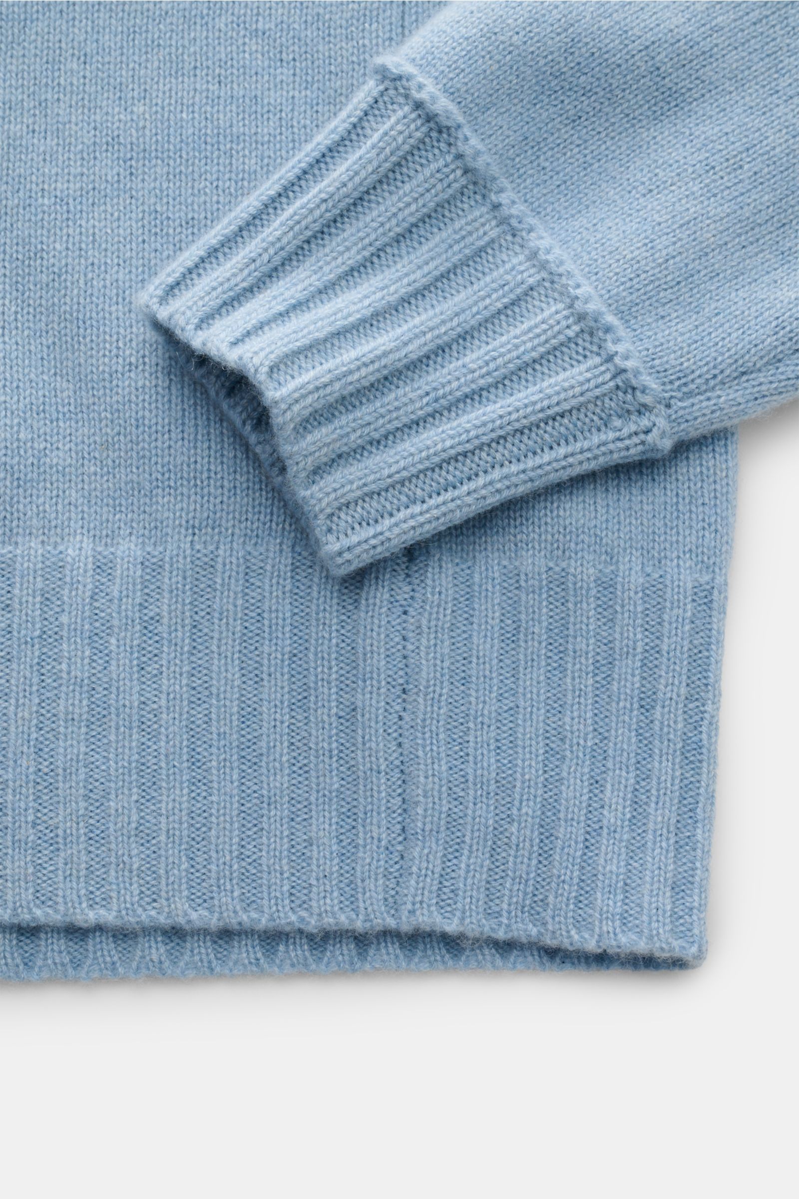 Close-up of the cuff and hem of the FTC Cashmere half-zip jumper light blue, showing ribbed cuffs and hem from a top-down perspective.

Stay cosy and warm in the colder months with this timeless half-zip jumper by FTC made of high-quality Fair Trade ca