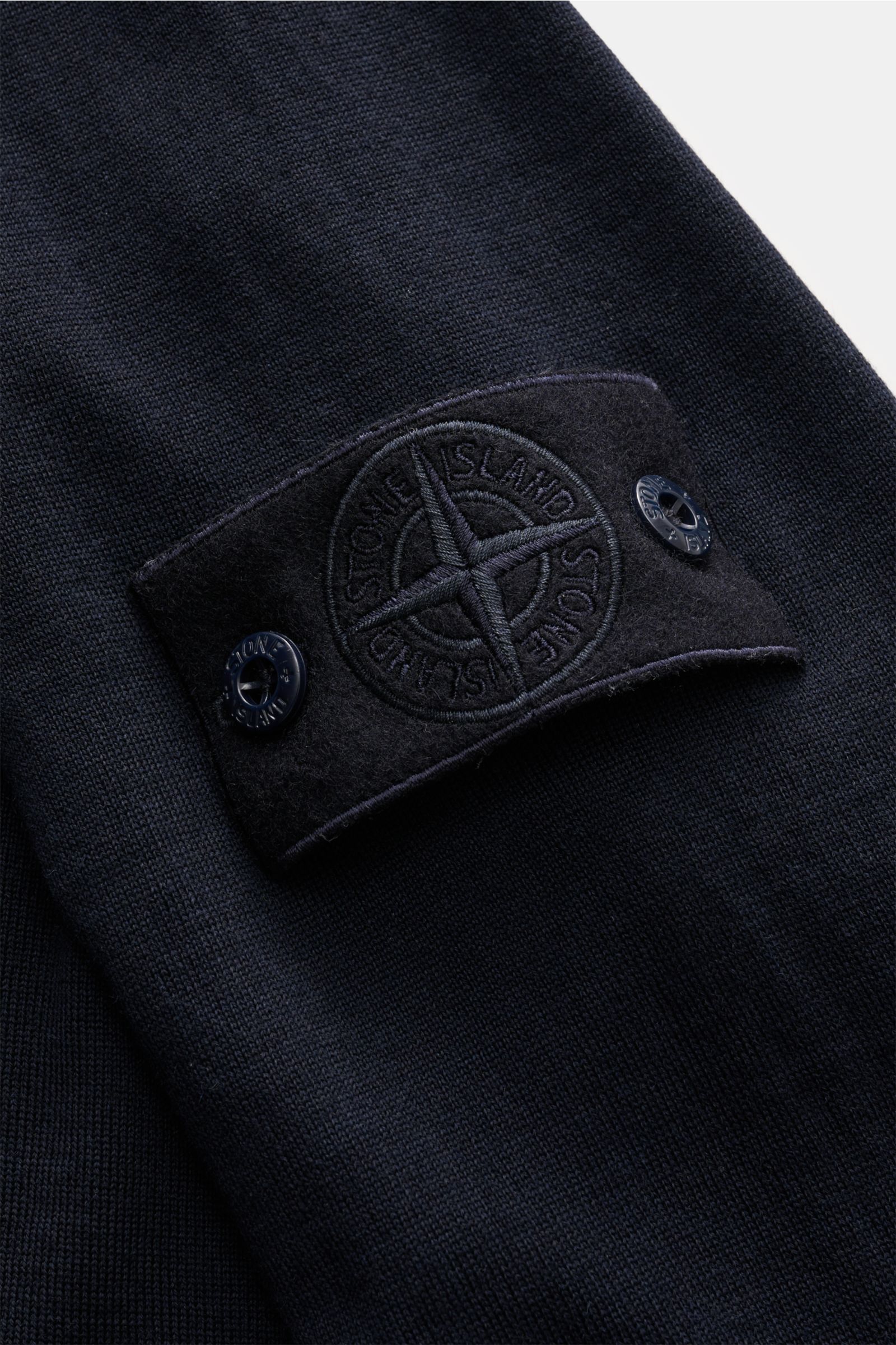 Stone Island Strickpolo 'Ghost Piece' navy, Detailaufnahme Ärmel mit monochromem Kompass-Badge, reine Schurwolle, weicher Griff.