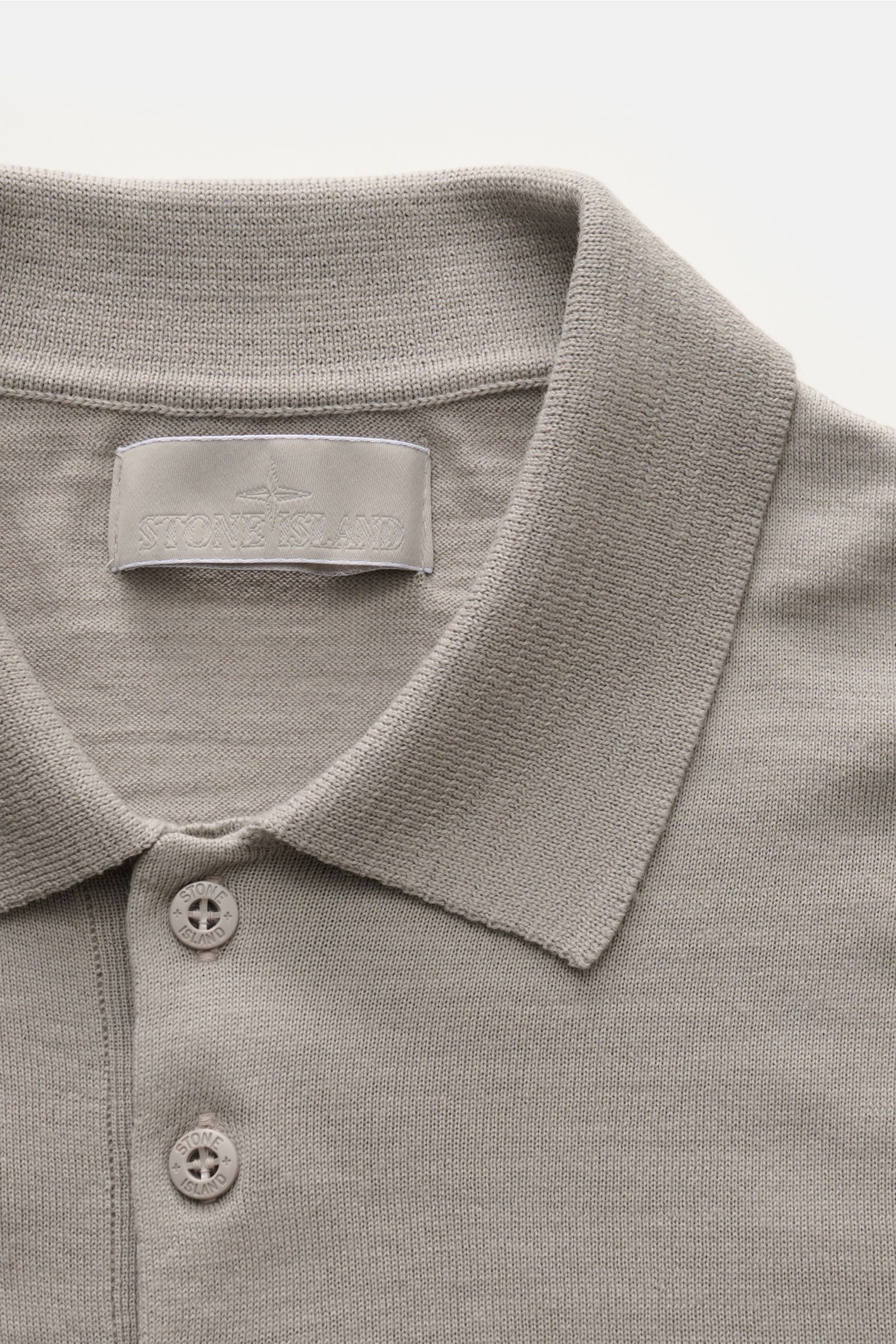Stone Island Strickpolo 'Ghost Piece' grau, Nahaufnahme von Kragen, Drei-Knopf-Leiste, weiche reine Schurwolle, feines Strickbild, tonales Kompass-Badge.
