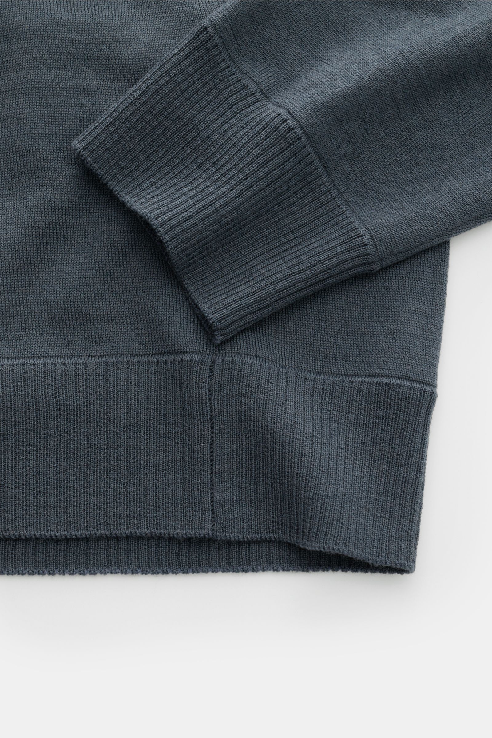 Stone Island Strickpolo 'Ghost Piece' dunkelgrau, Detailaufnahme von Ärmel und Saum, reine Schurwolle, weicher Griff, feines Strickbild, Rippbündchen, tonales Kompass-Badge.